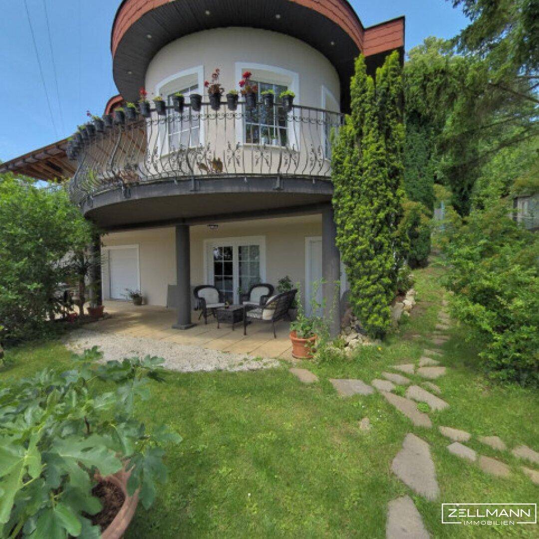 Erdgeschoss-Terrasse mit Sitzgelegenheiten und Zugang zum grünen Gartenbereich.