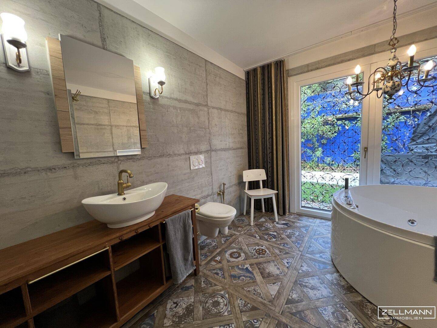 Modernes Badezimmer mit freistehender Badewanne, Einzelwaschbecken und Betonelementen.