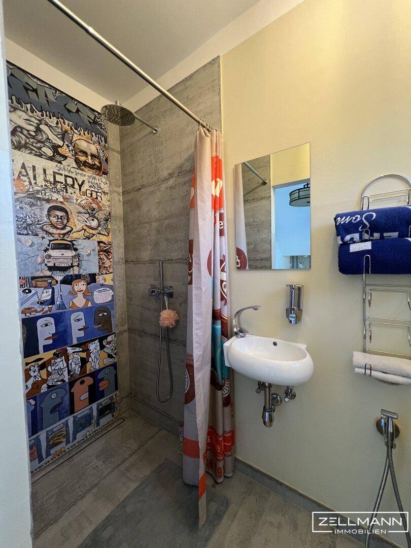 Kleines Badezimmer mit Dusche, Einzelwaschbecken und farbenfroher Wandgestaltung.