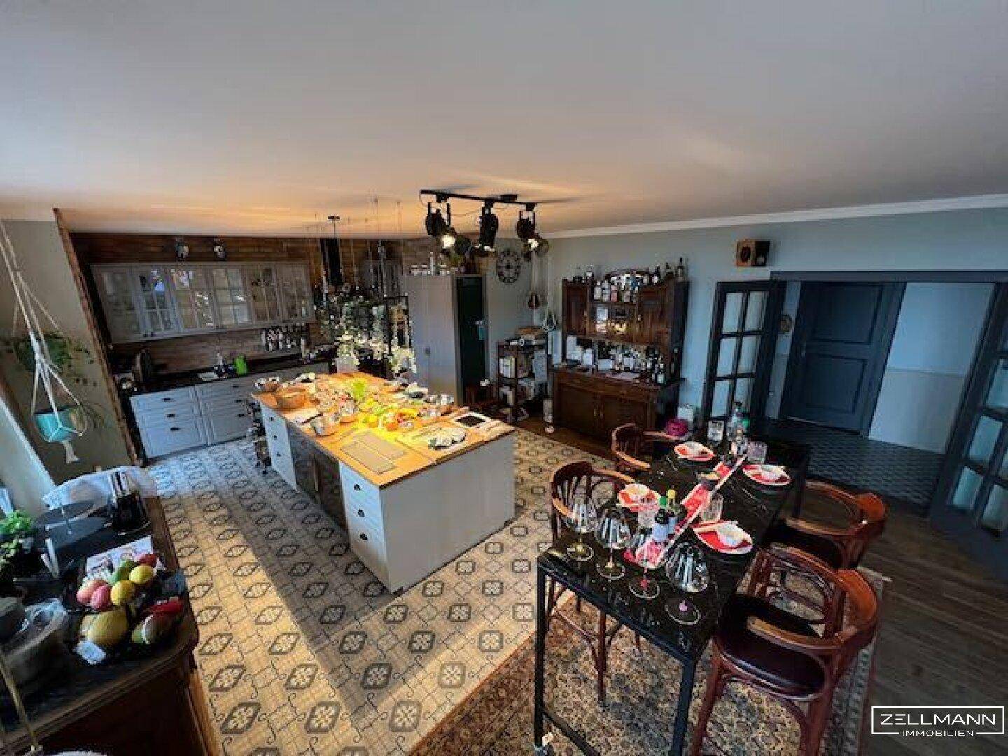 Geräumiger offener Wohn-Essbereich mit großer Kücheninsel und rustikalen Möbeln.