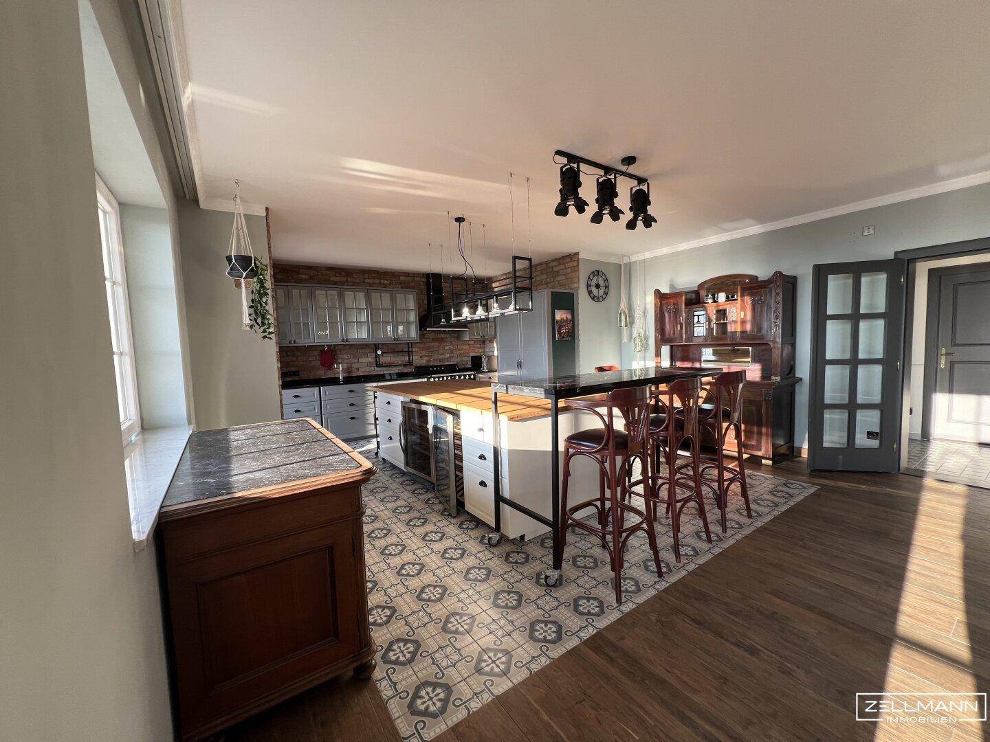 Offener Wohn-Essbereich mit Kücheninsel, Holzboden und viel Tageslicht.