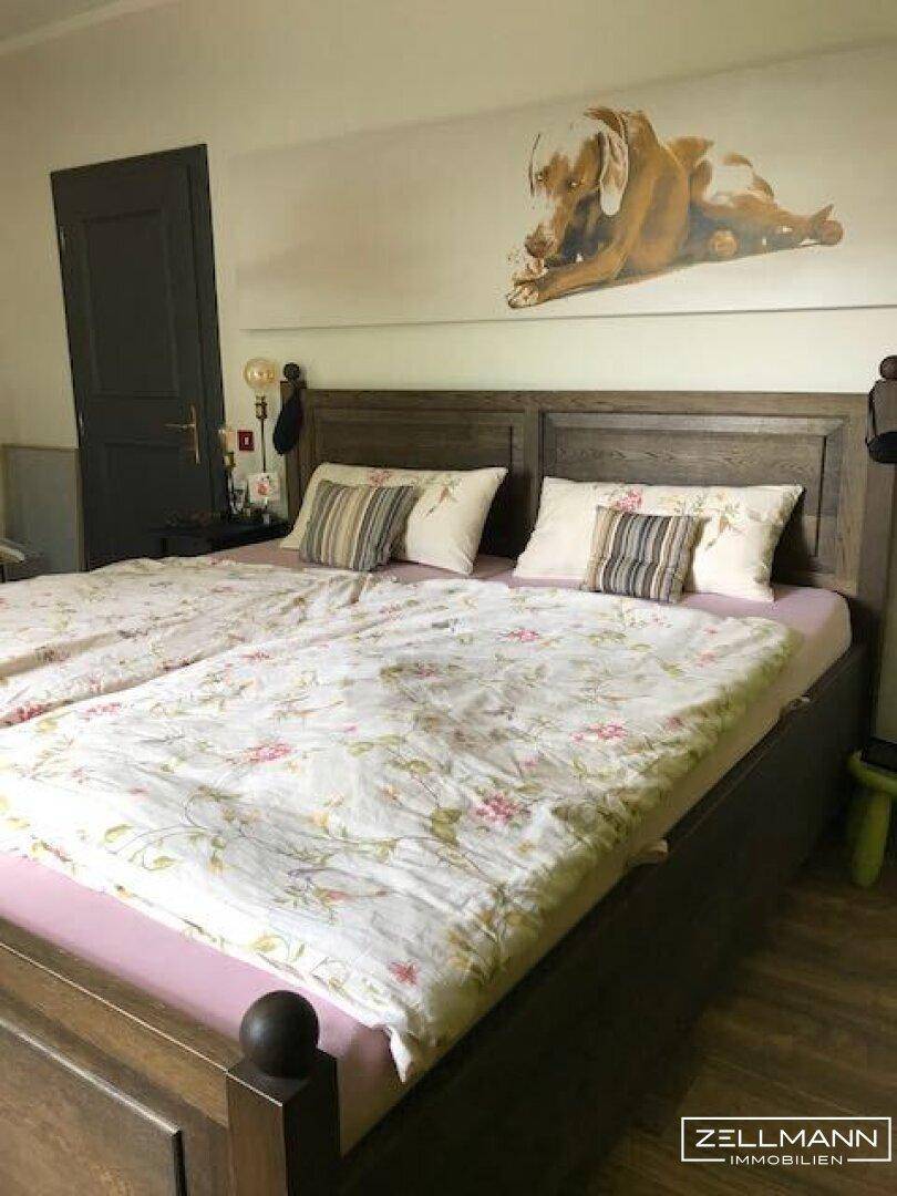 Gemütliches Schlafzimmer mit Holzbett, Holzboden und schlichter Einrichtung.