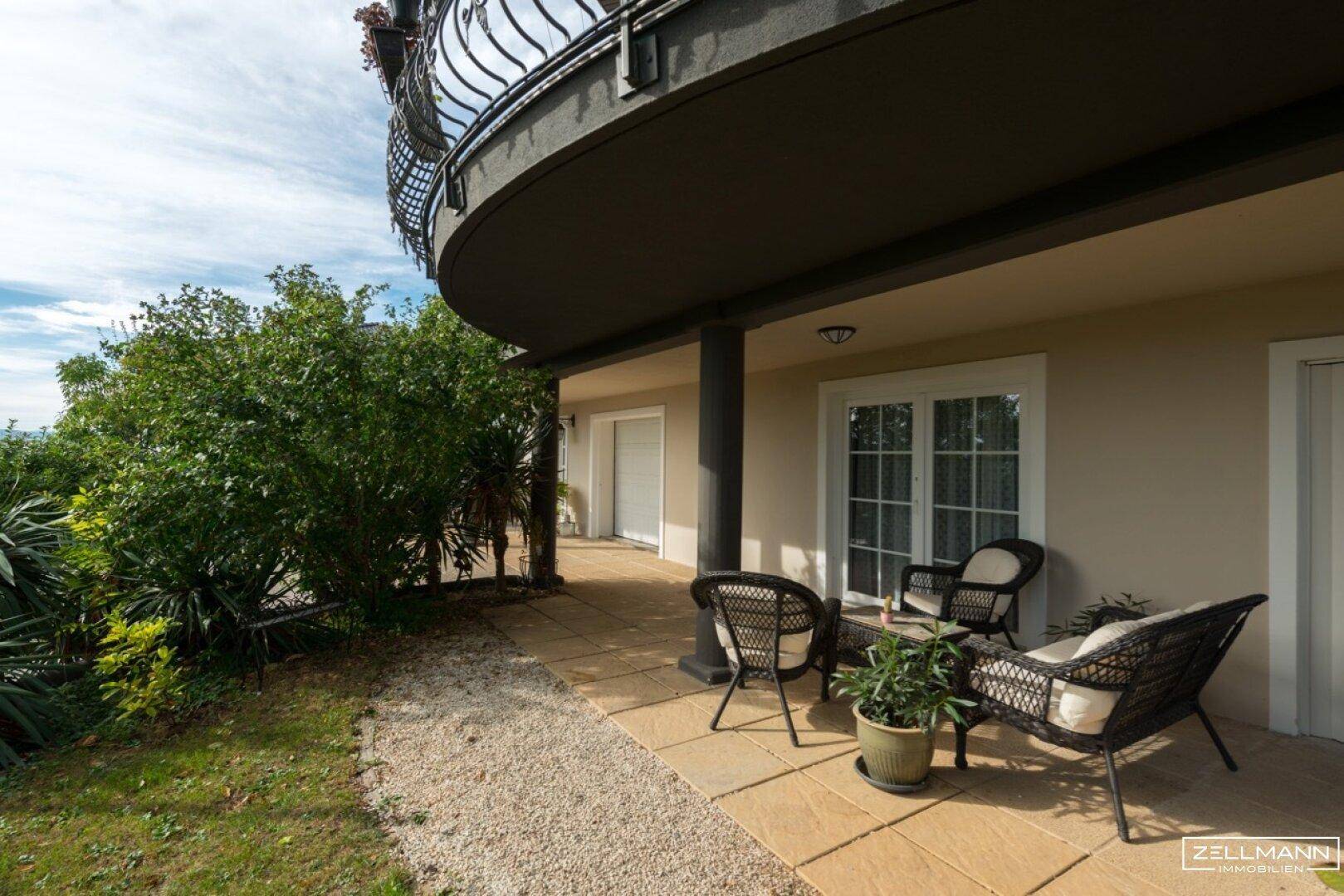 Erdgeschoss-Terrasse mit Sitzgelegenheiten und Zugang zum grünen Gartenbereich.