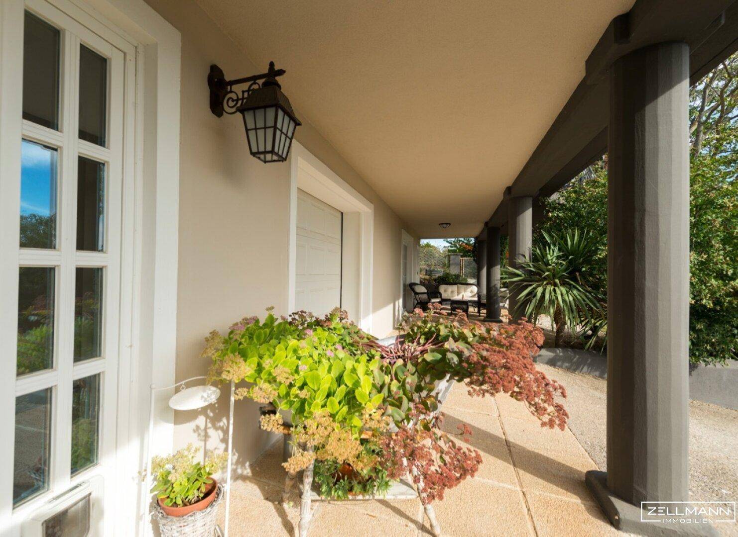 Überdachte Terrasse mit Außenbeleuchtung und Blick auf den Garten.