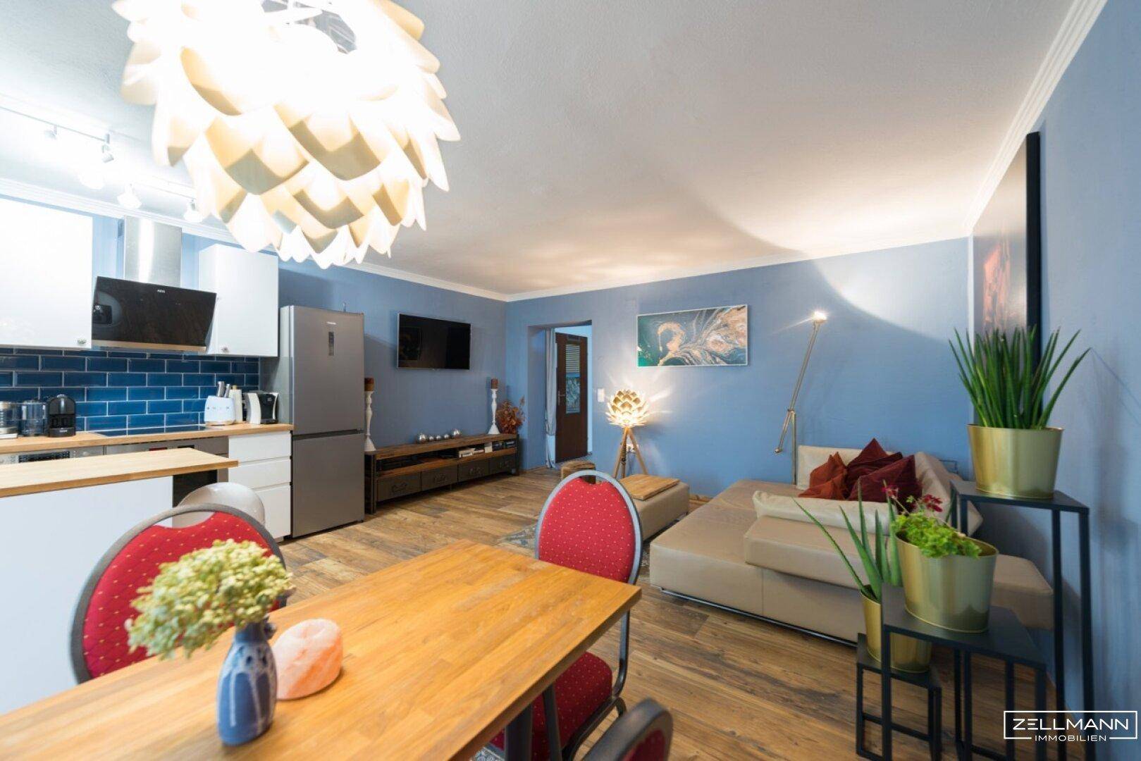 Offener Wohn-Essbereich mit blauen Wänden, Holzboden und moderner Einrichtung.