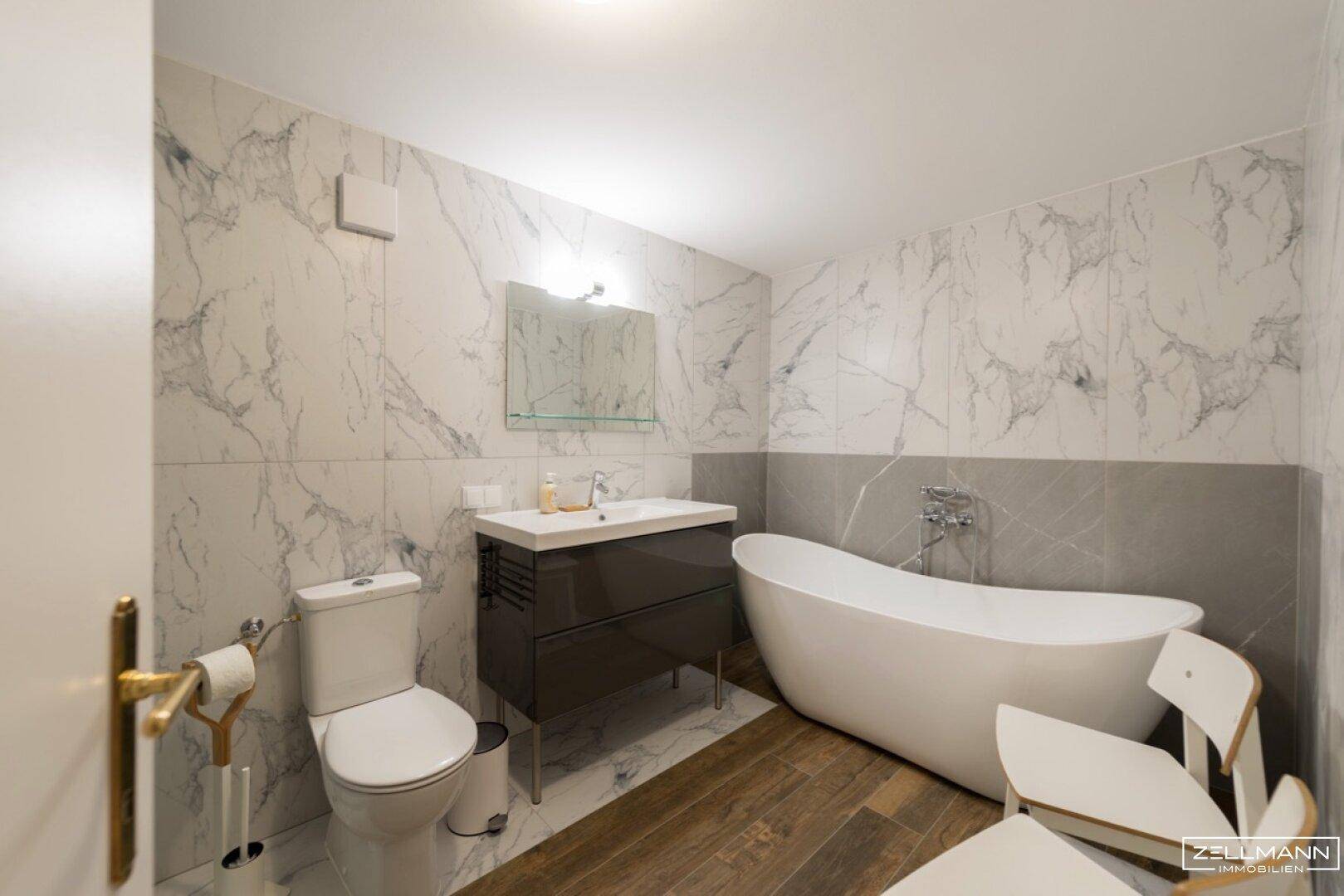 Modernes Badezimmer mit freistehender Badewanne, Marmorfliesen und Einzelwaschbecken.