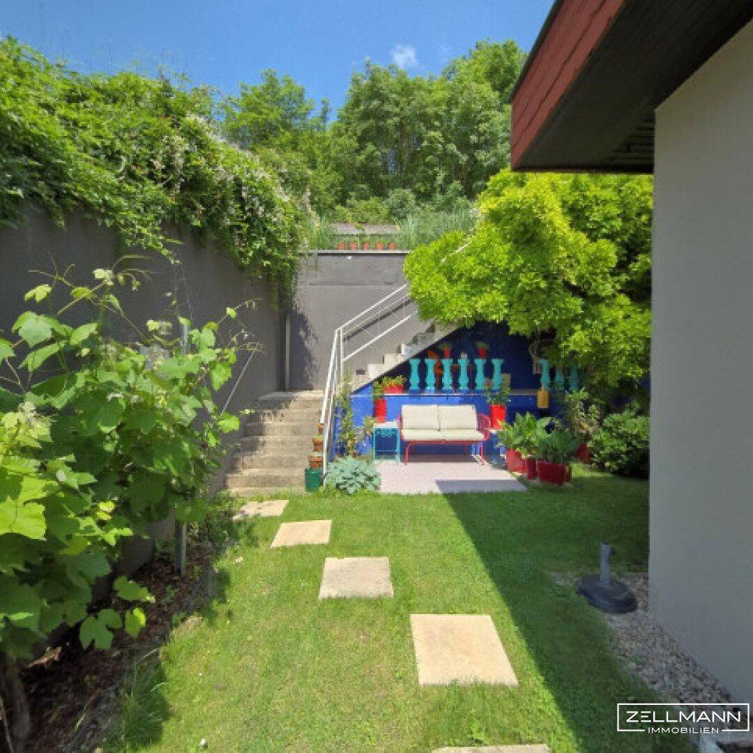 Mediterraner Gartenbereich mit Treppe, Rasenfläche und blauer Wand.