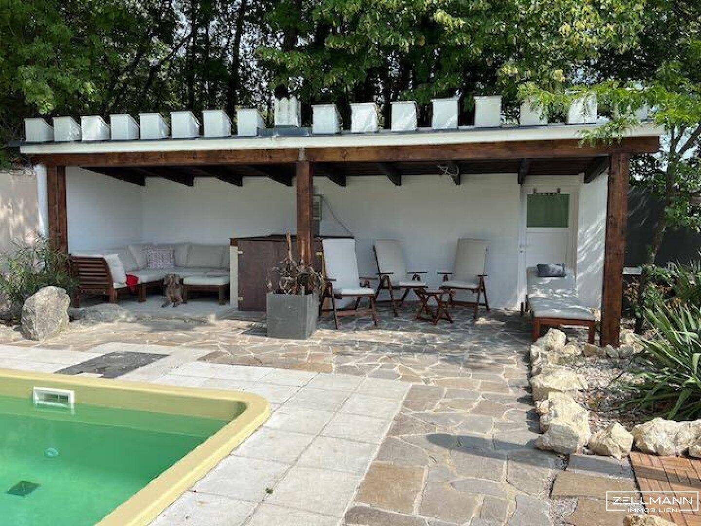 Überdachter Poolbereich mit Lounge-Möbeln und Essbereich neben dem Pool.