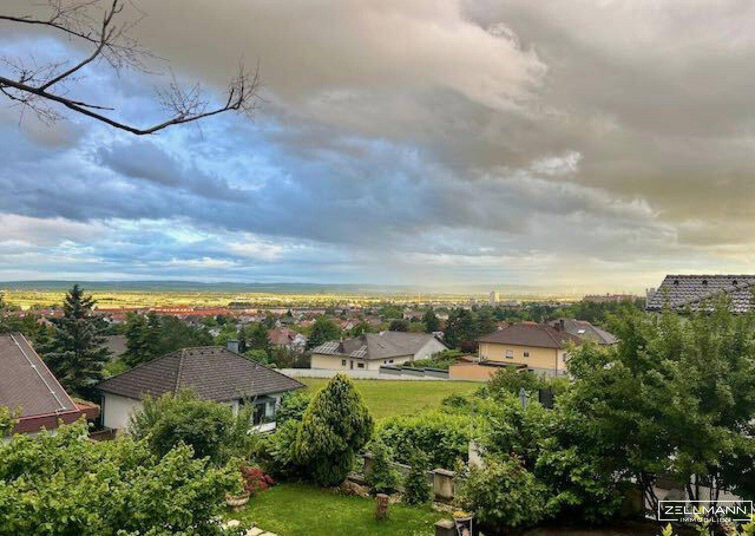 Weitläufiger Blick über die Stadt und die umliegende Landschaft bei bewölktem Himmel.