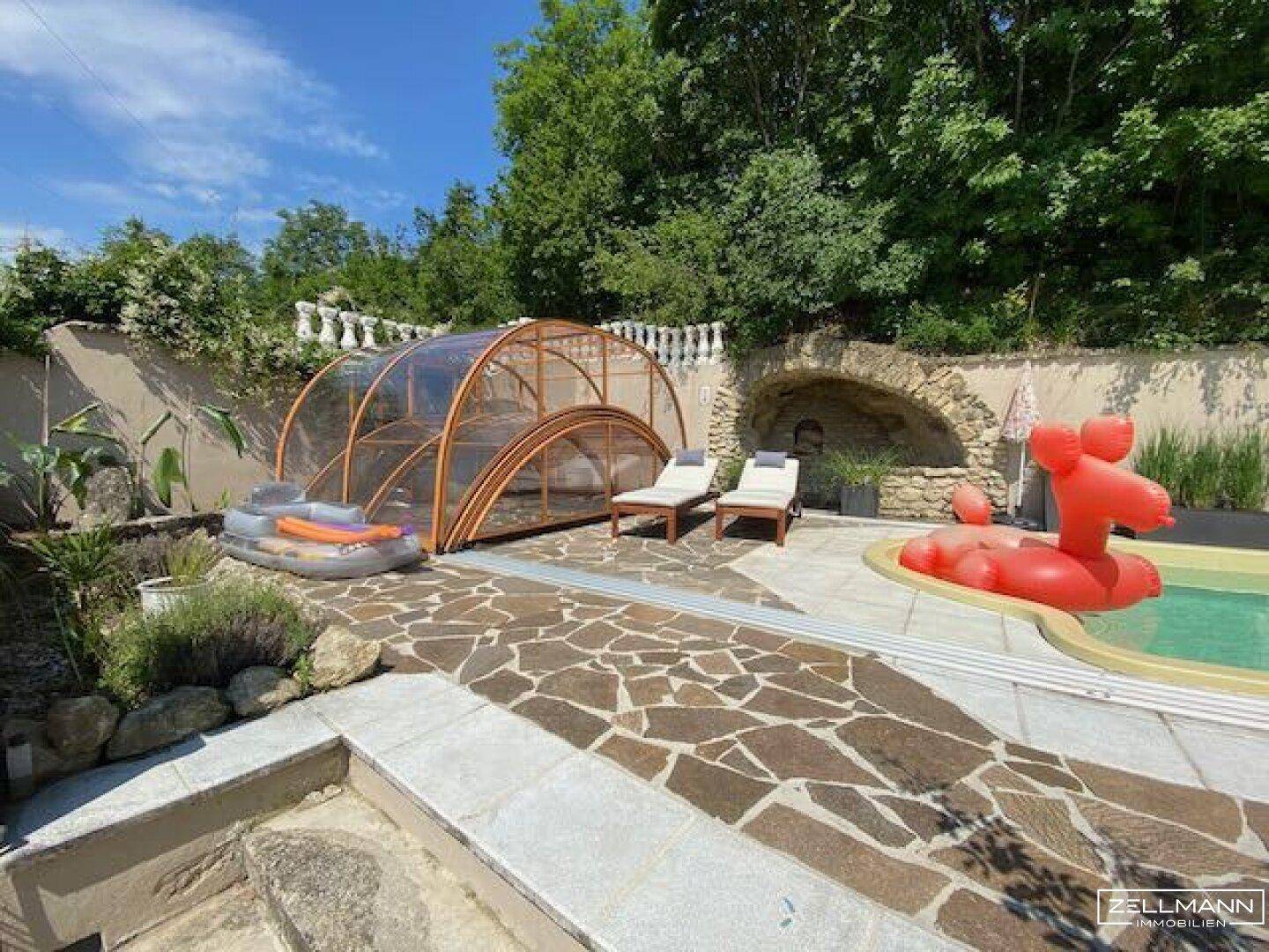 Poolbereich mit verschiebbarer Überdachung, Sonnenliegen und gepflasterter Fläche.