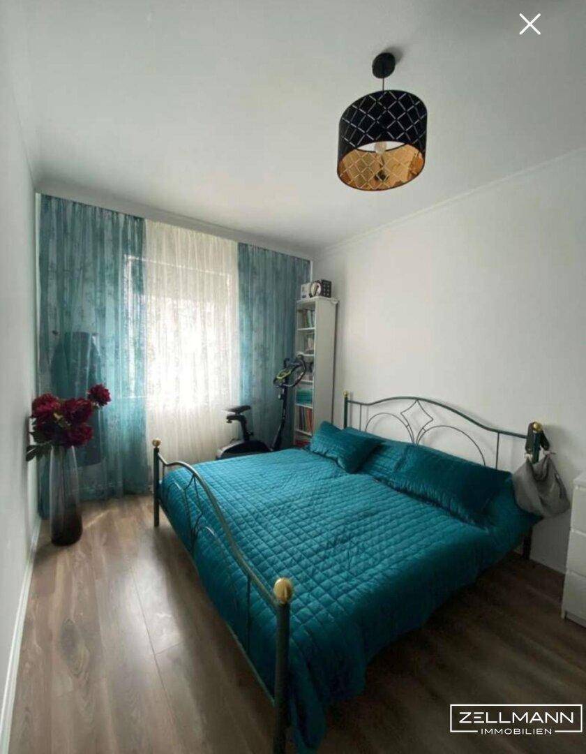 Schlafzimmer mit Doppelbett, Holzboden und türkisfarbenen Textilien.
