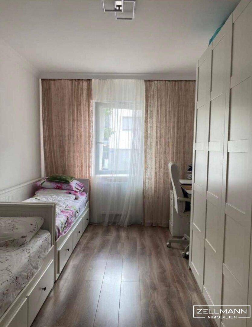 Helles Schlafzimmer mit zwei Einzelbetten, Schreibtisch und großem Kleiderschrank.