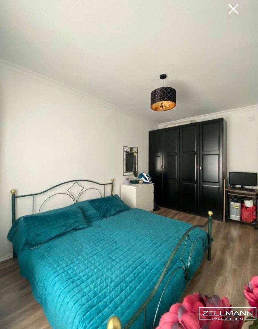 Schlafzimmer mit Doppelbett, dunklem Kleiderschrank und Holzboden.