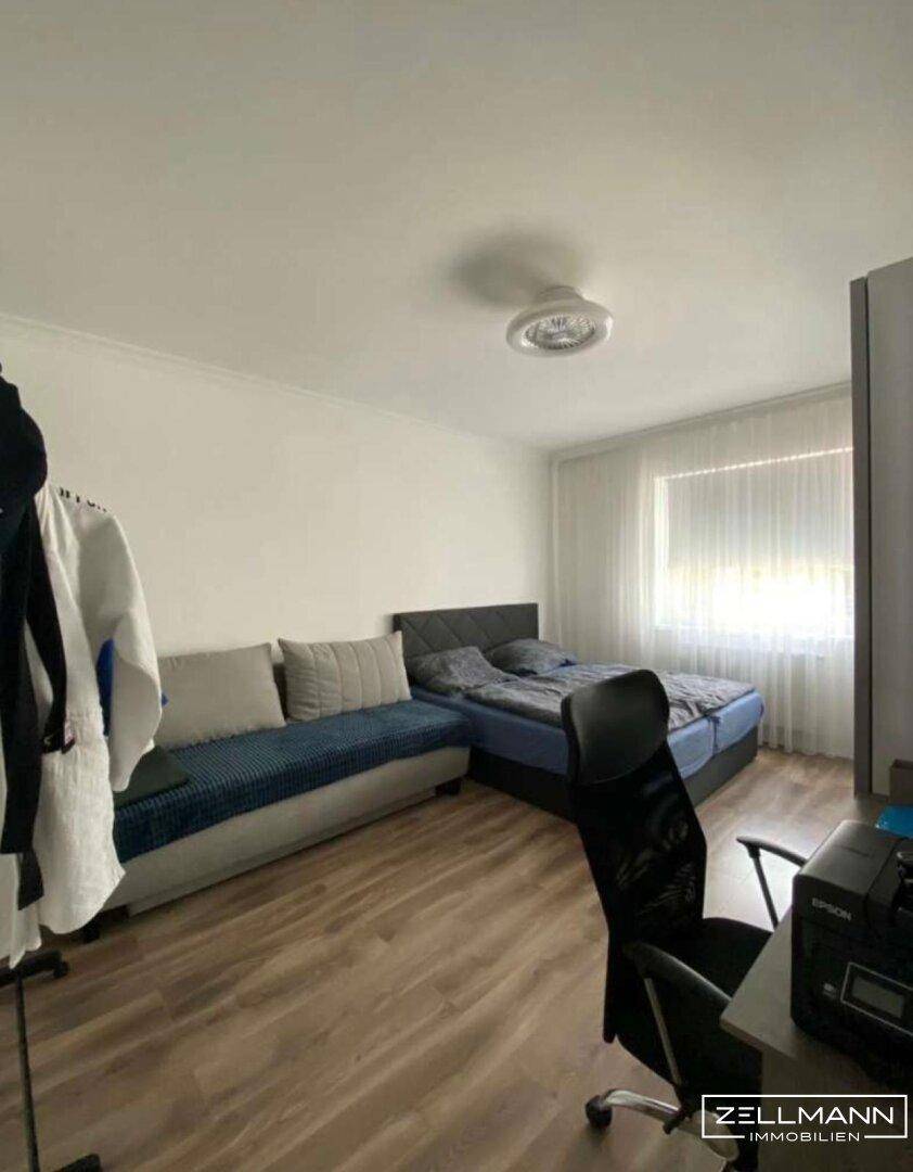 Schlafzimmer mit Doppelbett, Sofa und Schreibtisch, ideal für Gäste oder Kinder.