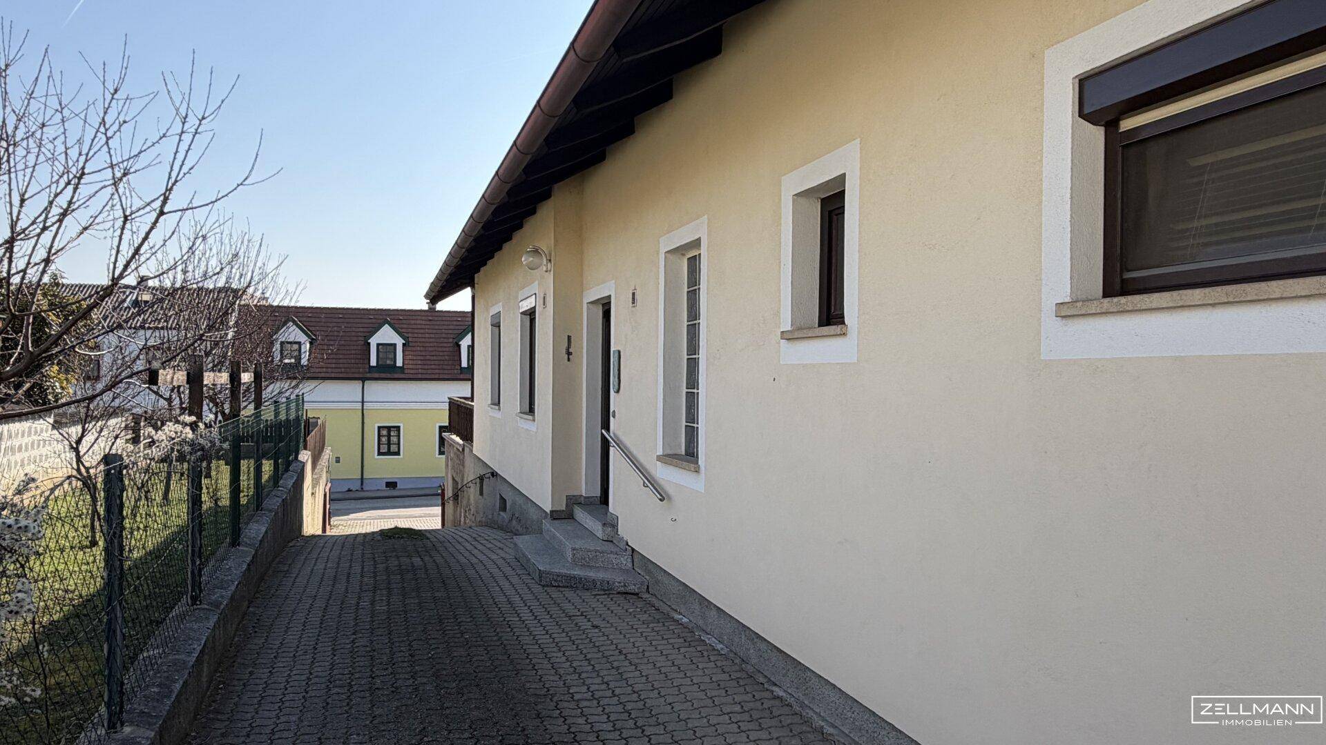 Seitenansicht des Hauses mit gepflastertem Weg und Blick auf die Nachbarschaft.
