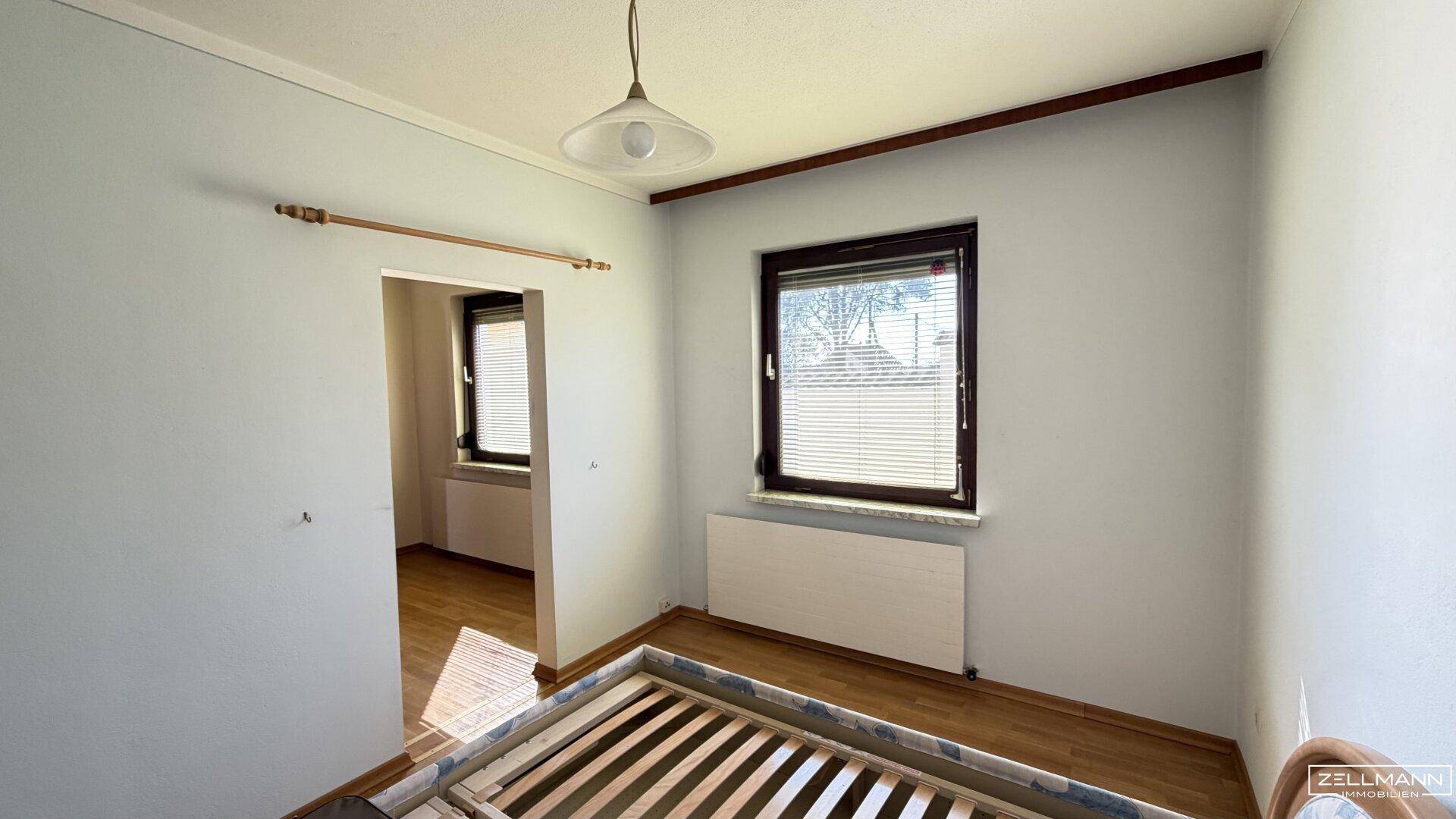Helles Schlafzimmer mit Parkettboden und Fenster, ideal für ein Kinderzimmer.