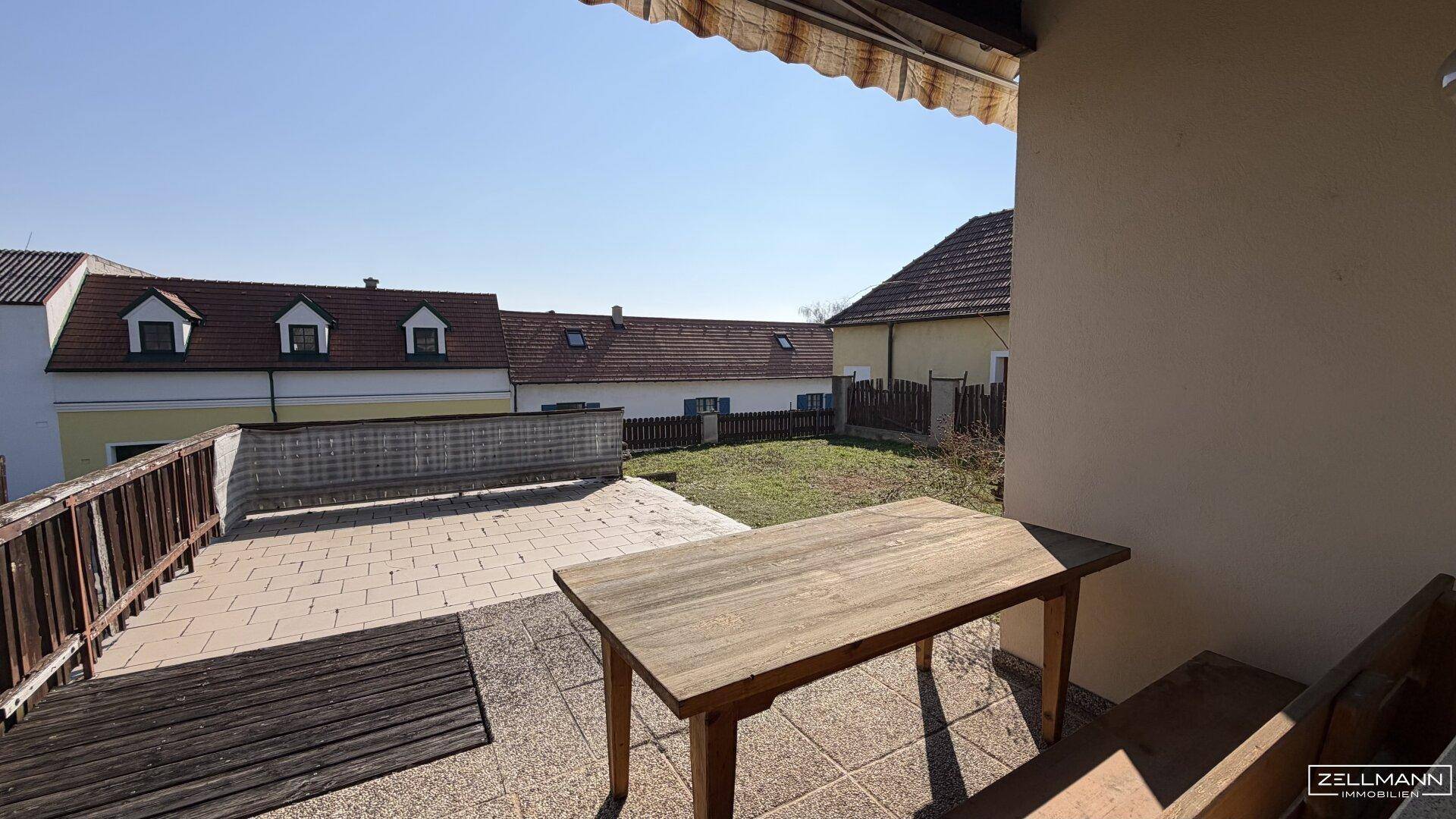 Große Terrasse mit Holztisch und Blick auf die umliegenden Häuser.