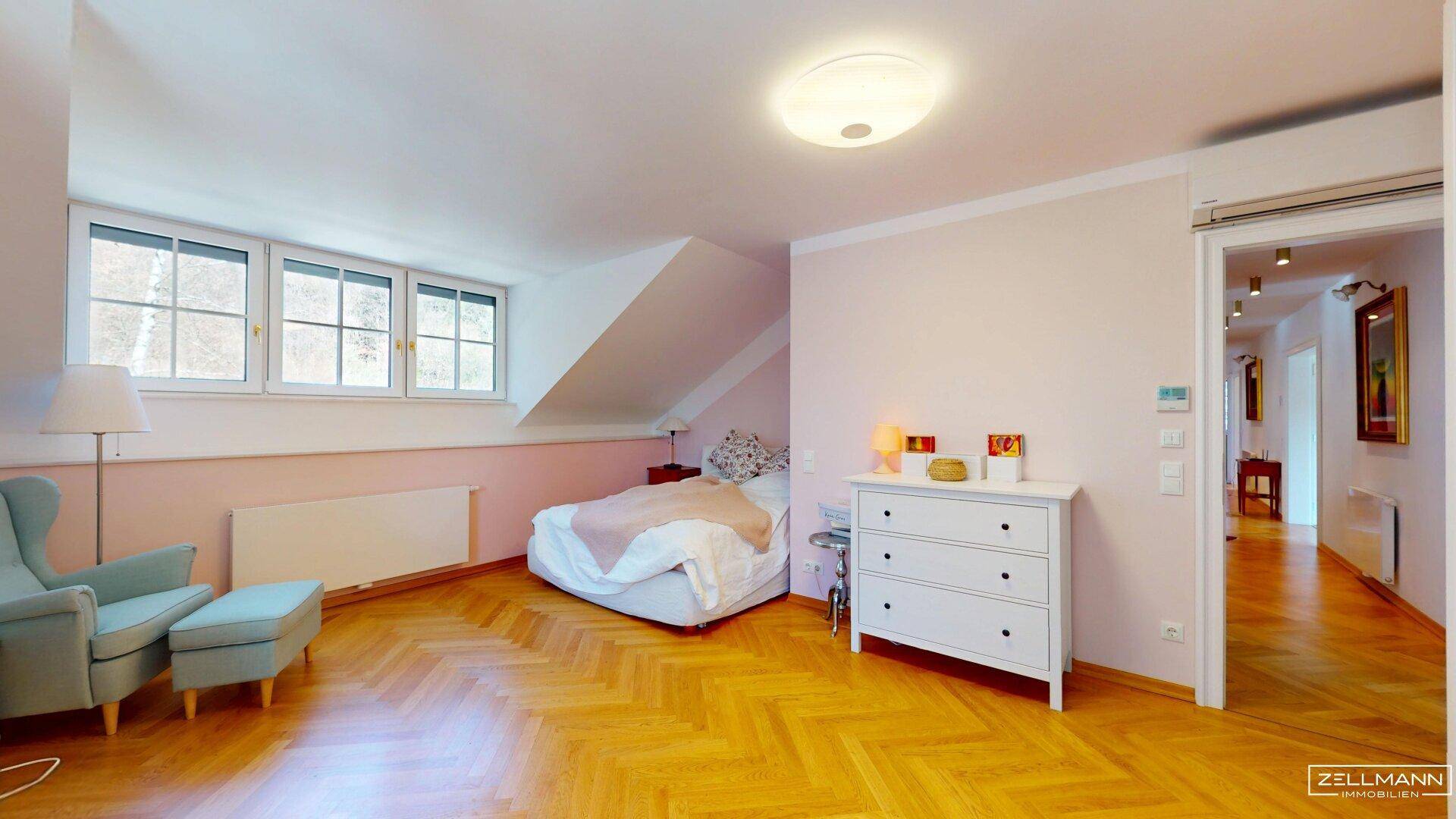 Gemütliches Schlafzimmer im Dachgeschoss mit Schrägen, Parkettboden und hellen Wänden.