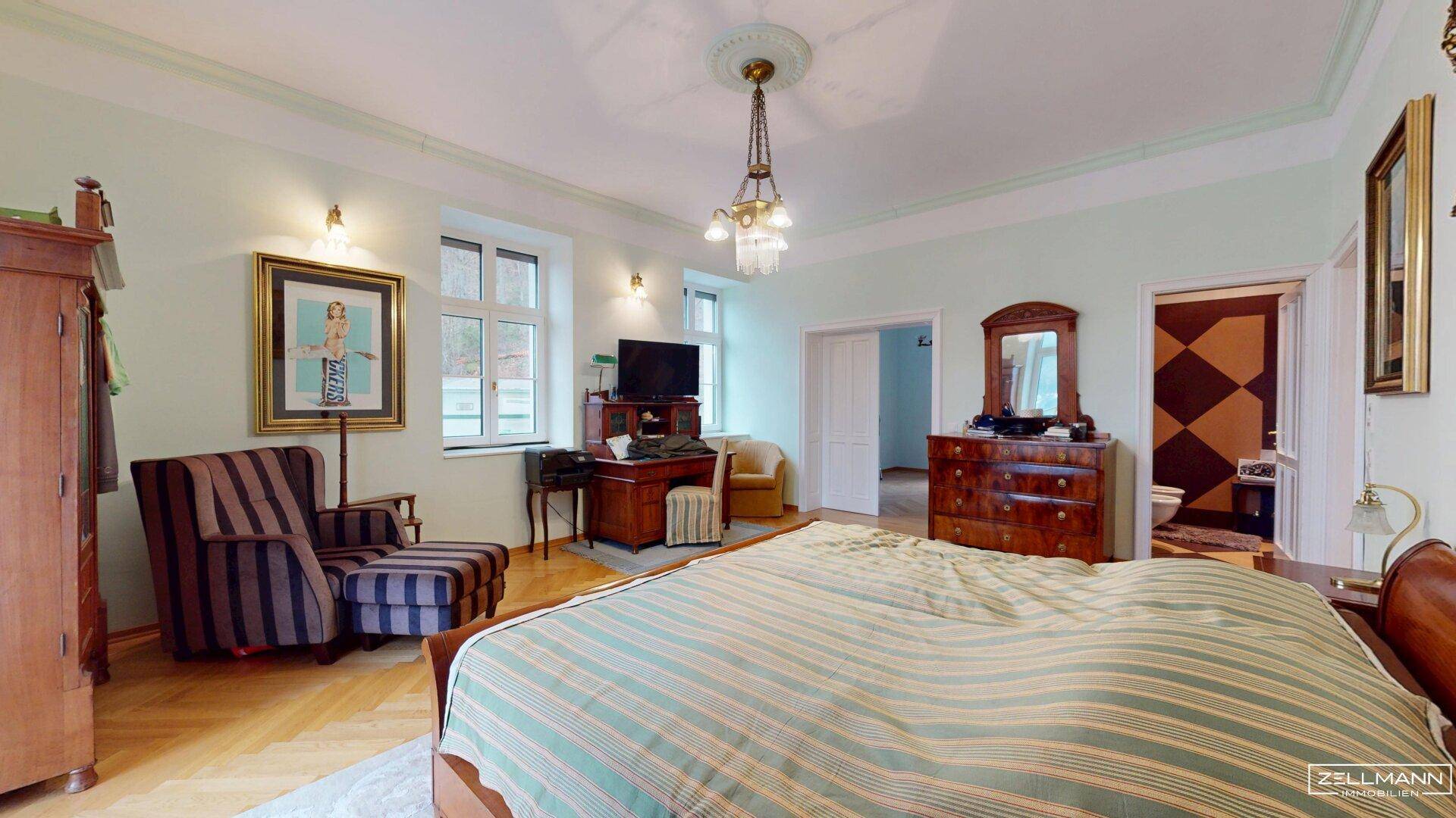 Geräumiges Schlafzimmer mit Parkettboden, klassischem Mobiliar und angrenzendem Bad.
