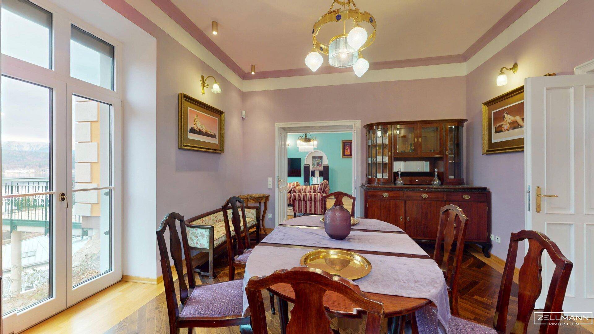 Elegantes Esszimmer mit dunklem Fischgrätparkett, lila Wänden und Blick nach draußen.