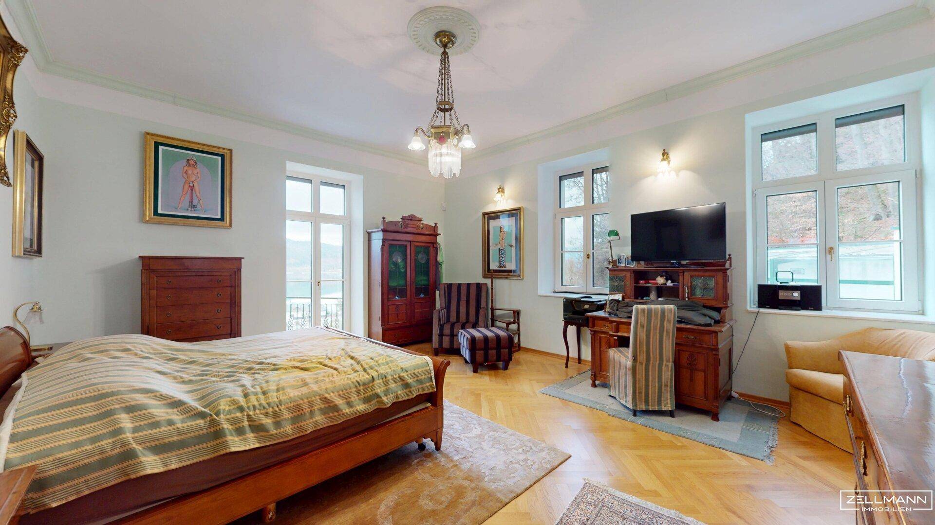Geräumiges Schlafzimmer mit Parkettboden, klassischem Mobiliar und Blick ins Grüne.