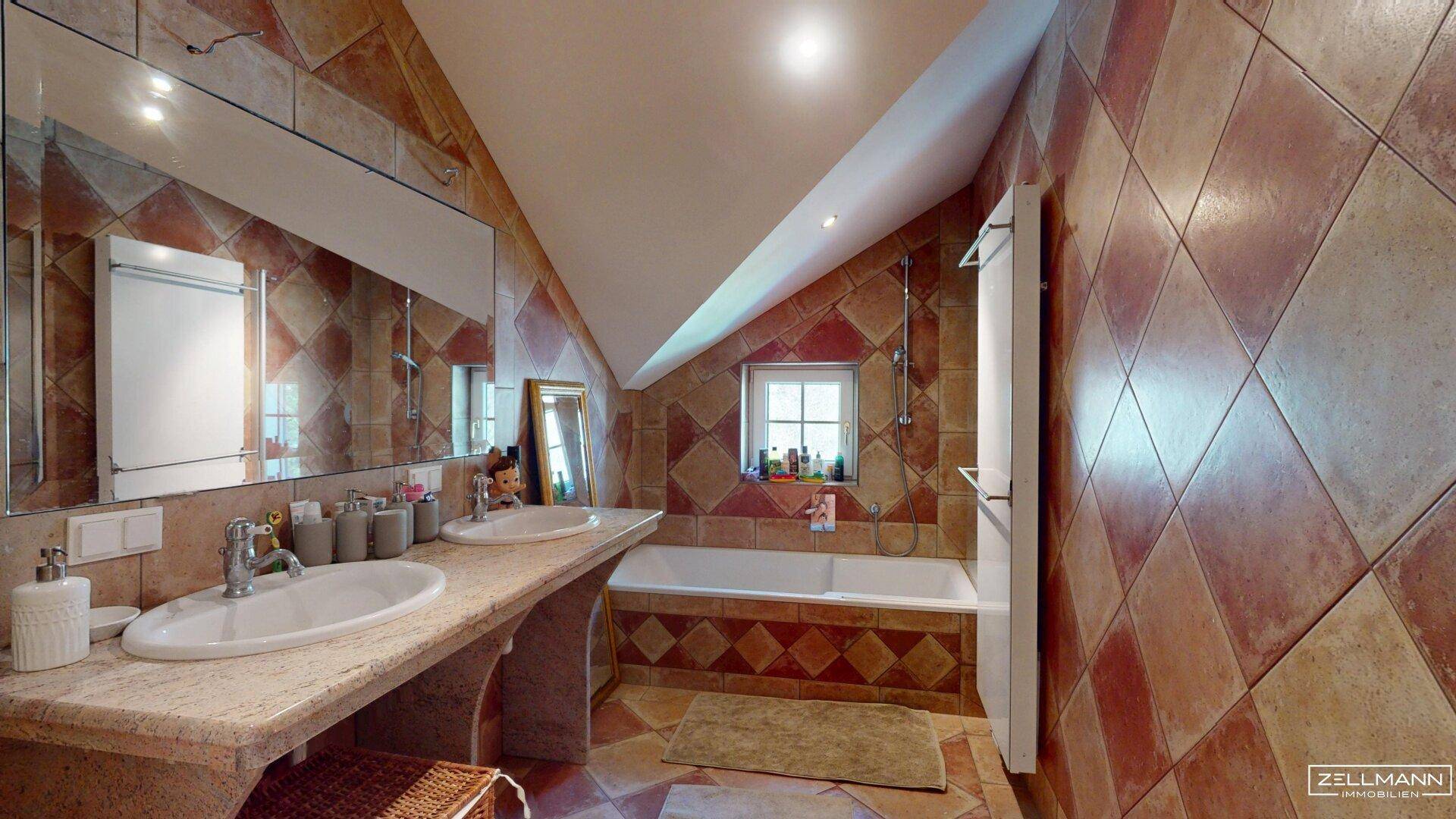 Geräumiges Badezimmer im Dachgeschoss mit Badewanne, Doppelwaschbecken und Fliesen.