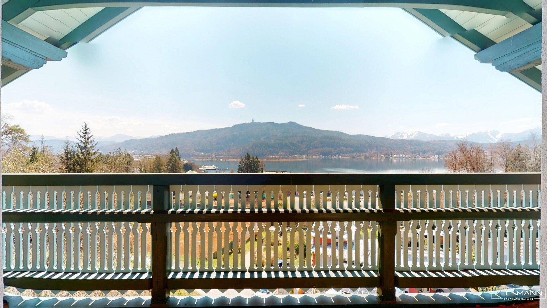 Traditioneller Holzbalkon mit geschnitztem Geländer und weitem Blick auf den See und die Berge.