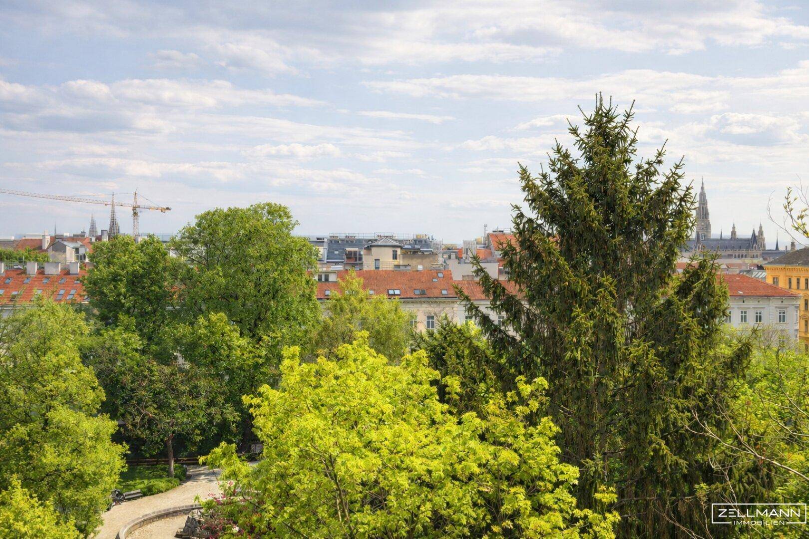Panoramablick über die Stadt mit grünen Bäumen und historischen Gebäuden im Hintergrund.