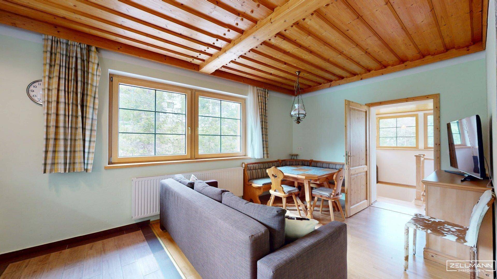 Heller Wohn- und Essbereich mit Holzbalkendecke, Sofa und traditioneller Eckbank.