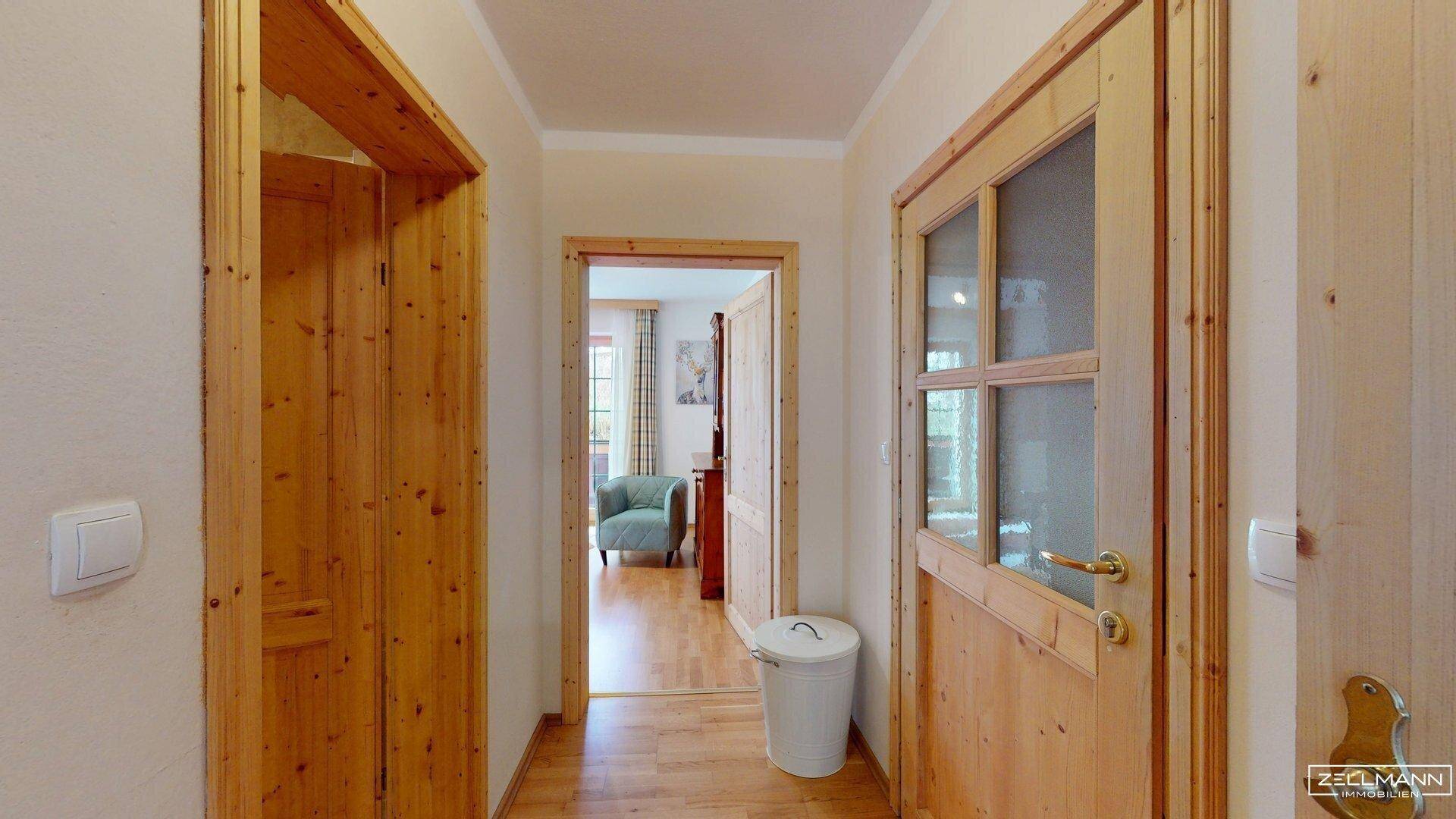 Heller Flur mit Holztüren und Holzboden, der zu weiteren Räumen führt.