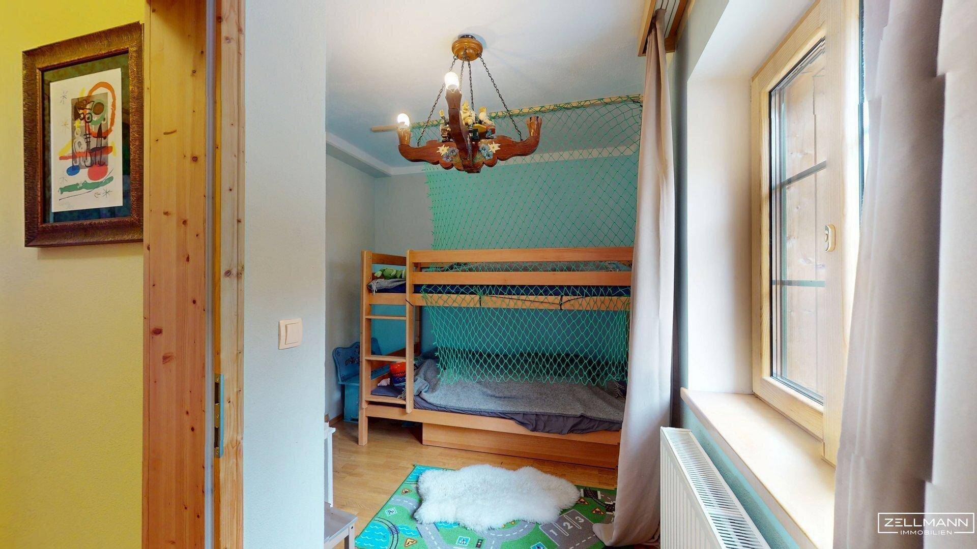 Kinderzimmer mit Etagenbett, farbenfroher Dekoration und Blick ins Grüne.