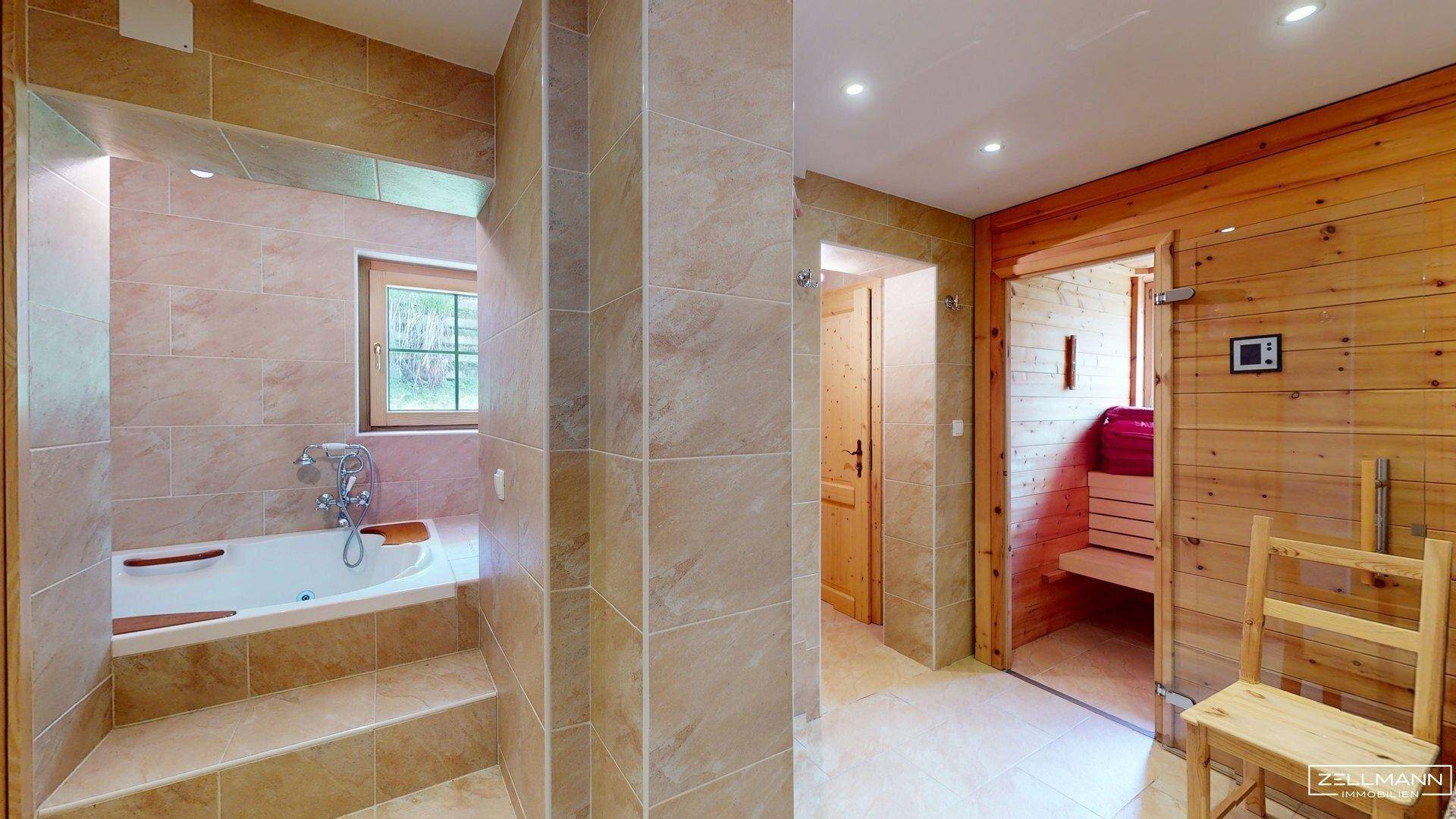 Großzügiges Badezimmer mit Whirlpool-Badewanne und Sauna, hell gefliest und holzvertäfelt.