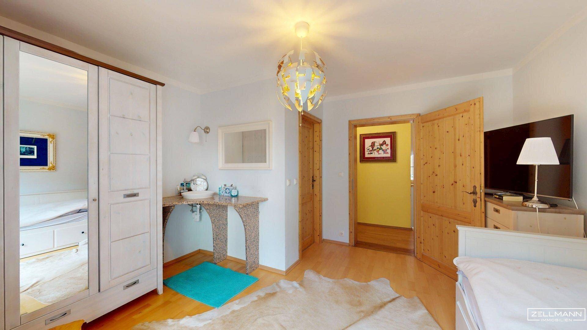 Gemütliches Schlafzimmer mit Holzboden, weißem Kleiderschrank und einem dekorativen Teppich.