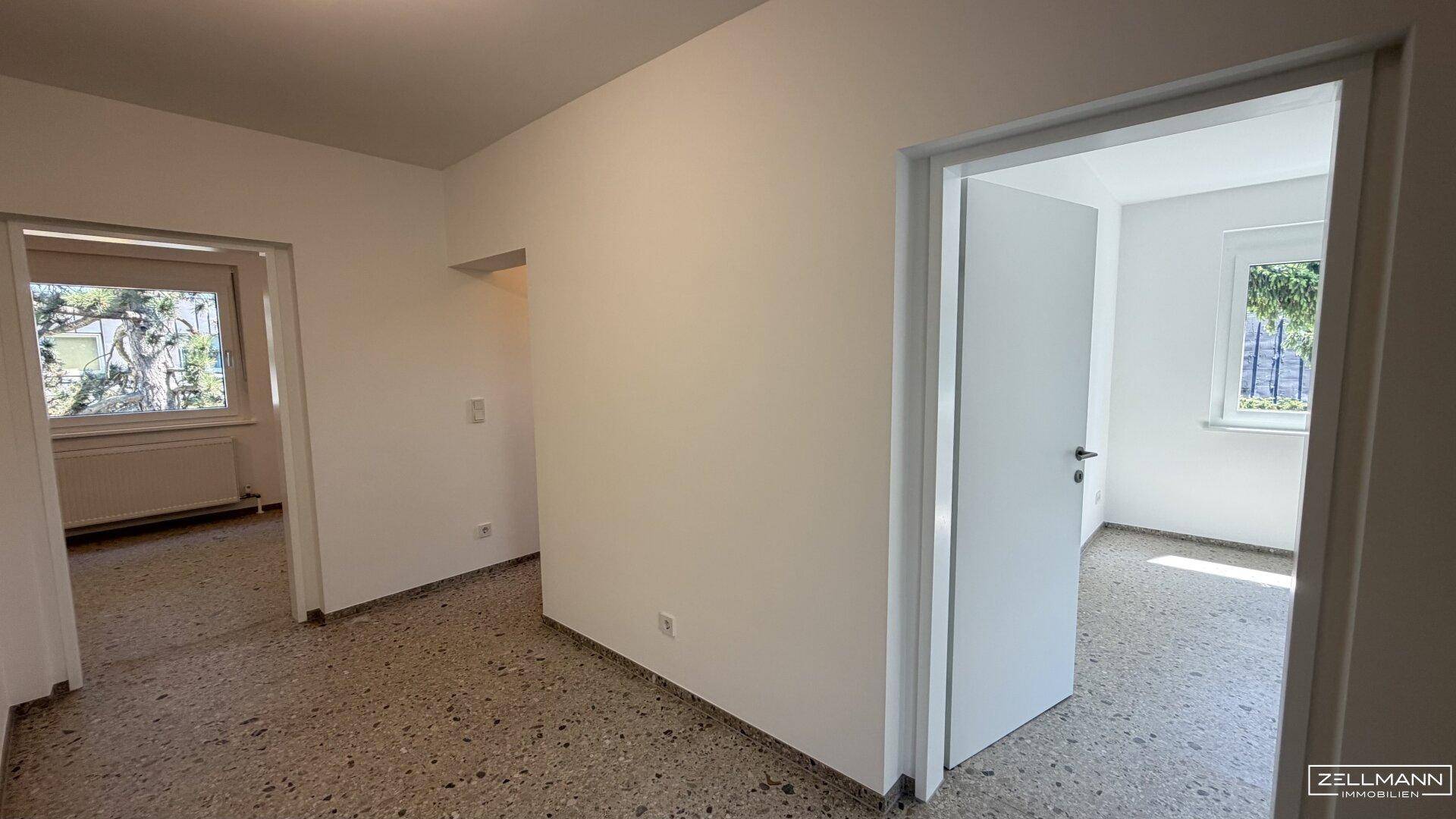 Heller Flur mit Zugang zu mehreren Zimmern und einheitlichem Bodenbelag.