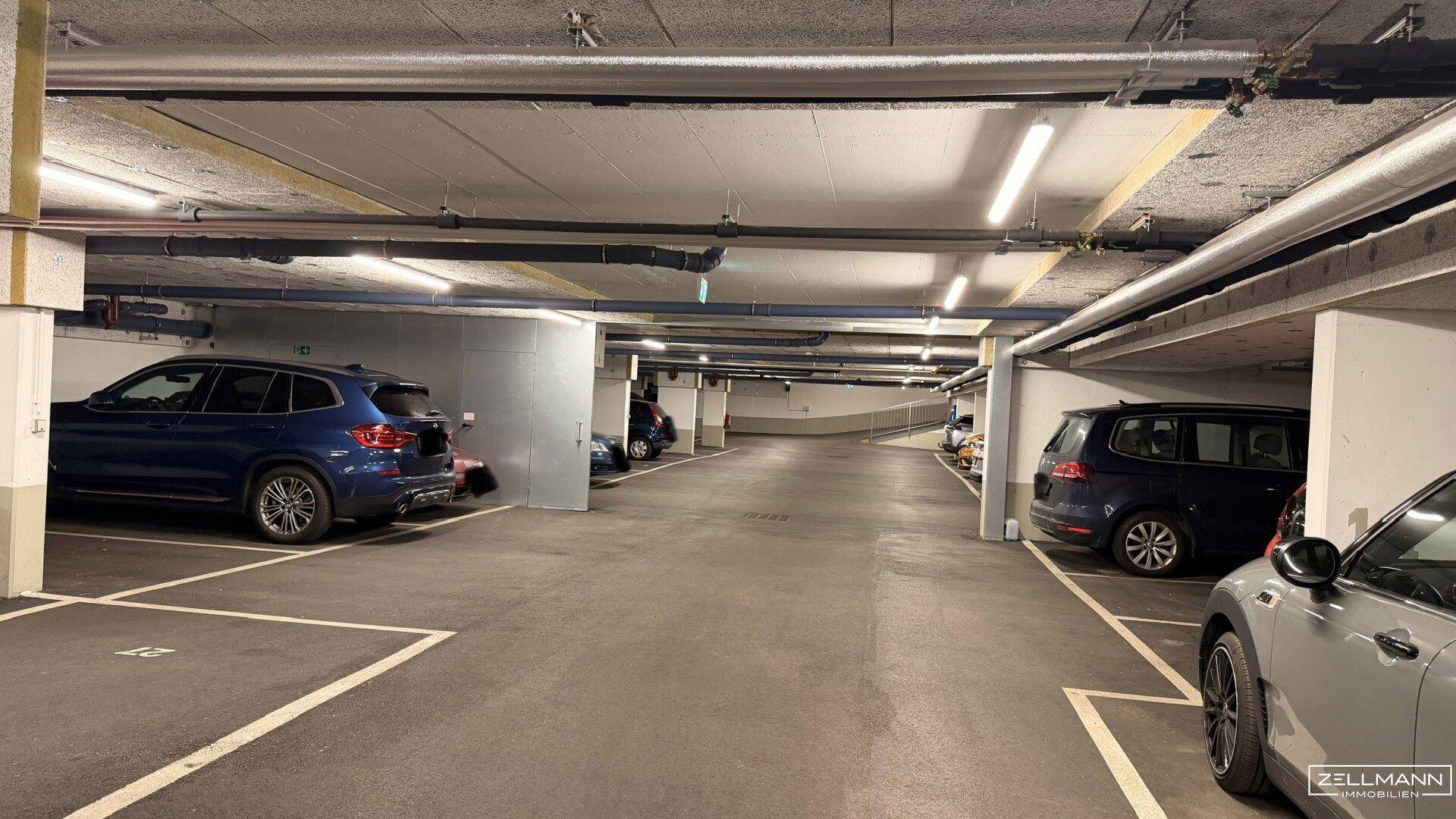 Geräumige Tiefgarage mit mehreren Stellplätzen und guter Beleuchtung durch Leuchtstoffröhren.