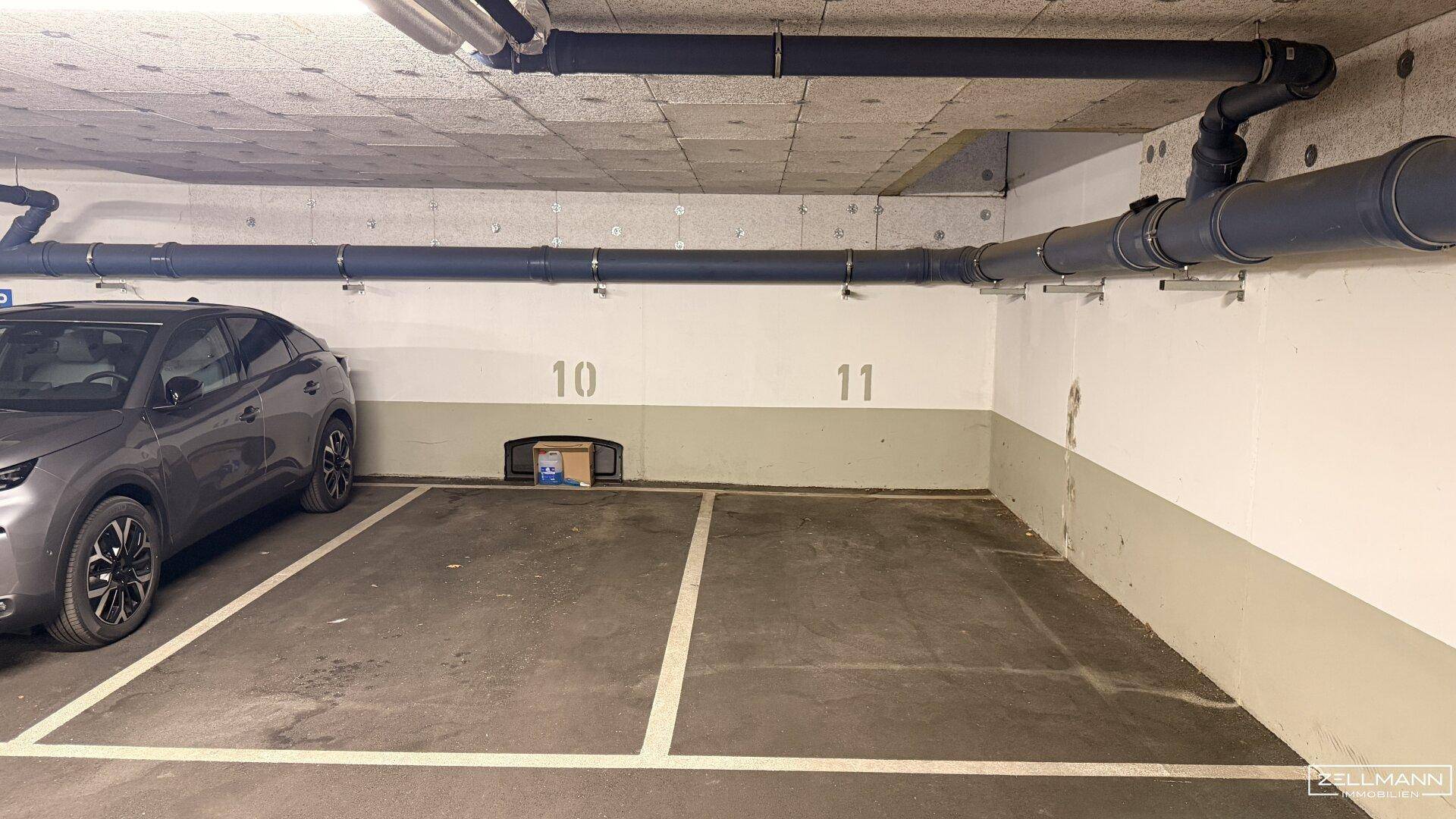 Innenansicht eines Tiefgaragenstellplatzes Nummer 11 mit sichtbaren Rohren an der Decke.