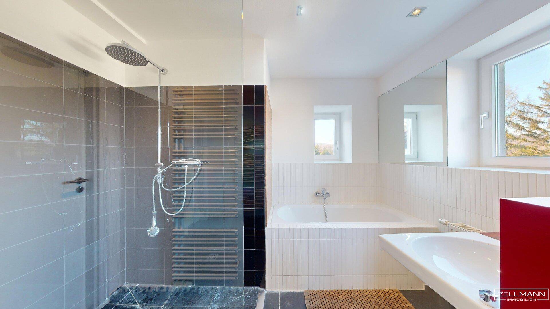 Modernes Badezimmer mit großer Regendusche, Badewanne und beheiztem Handtuchhalter.