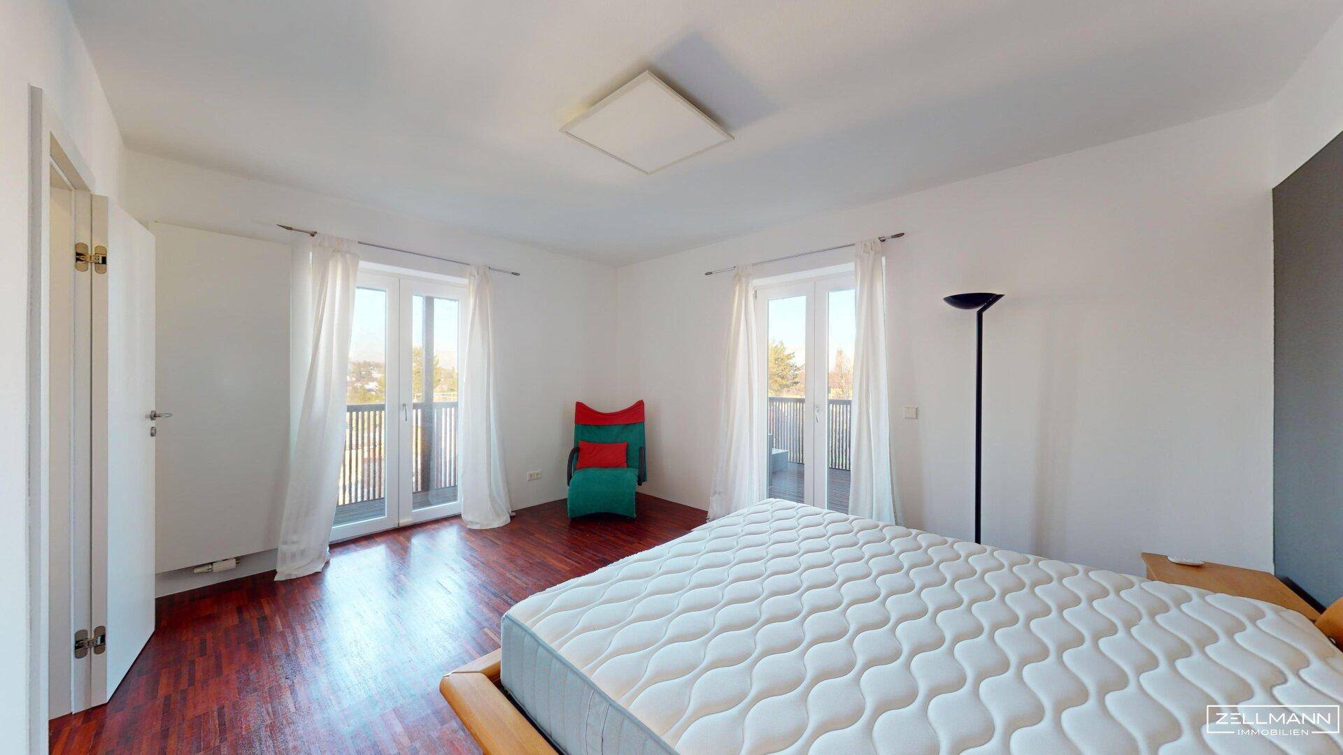 Geräumiges Schlafzimmer mit Holzboden und Zugang zu einem französischen Balkon.