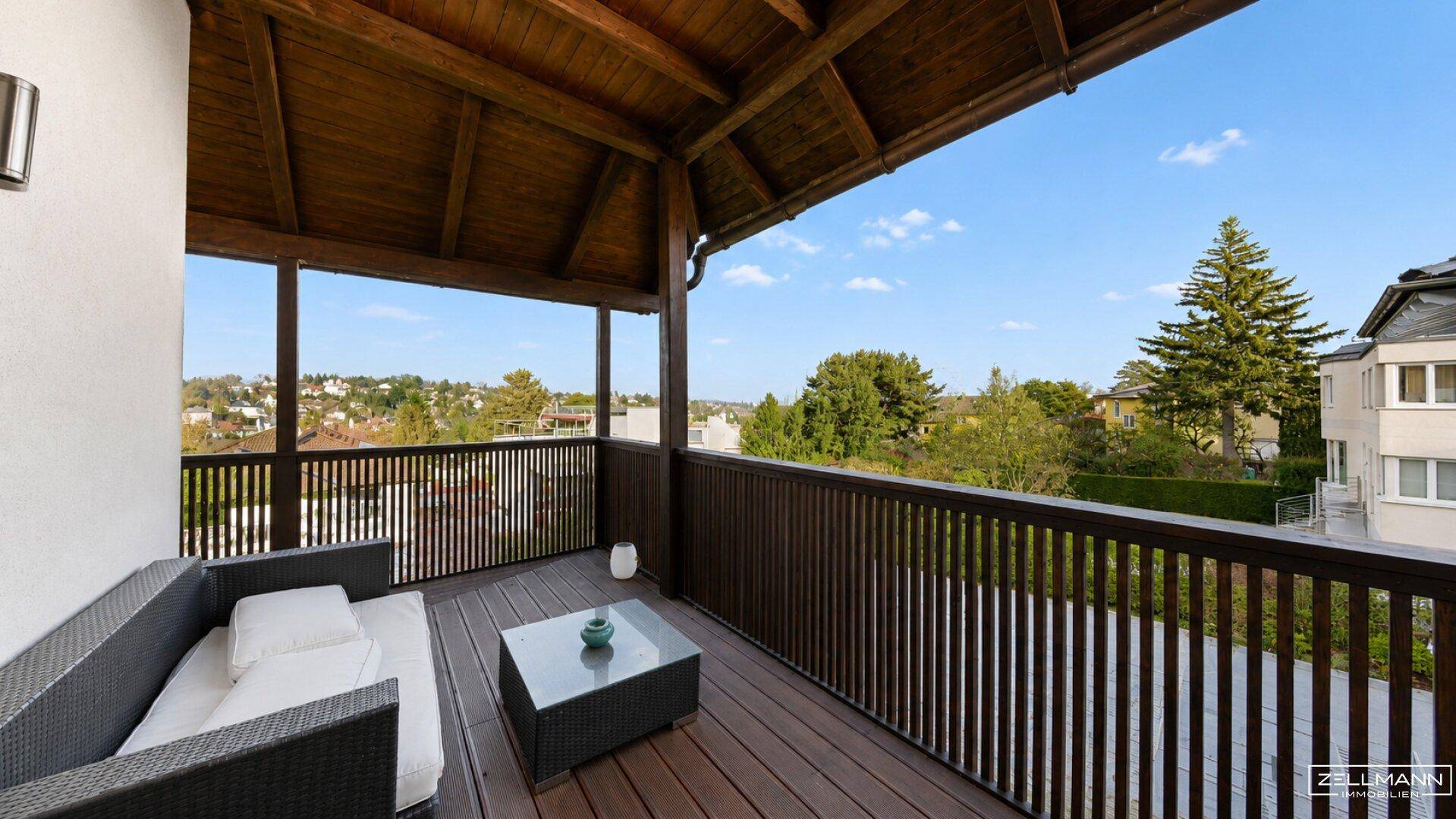 Überdachter Balkon mit Holzboden und gemütlichen Sitzmöbeln, bietet einen weiten Blick.