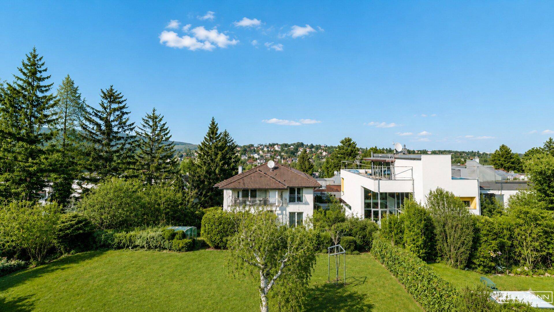 Weitläufige Grünfläche mit Blick auf die umliegende Wohngegend und bewaldete Hügel.