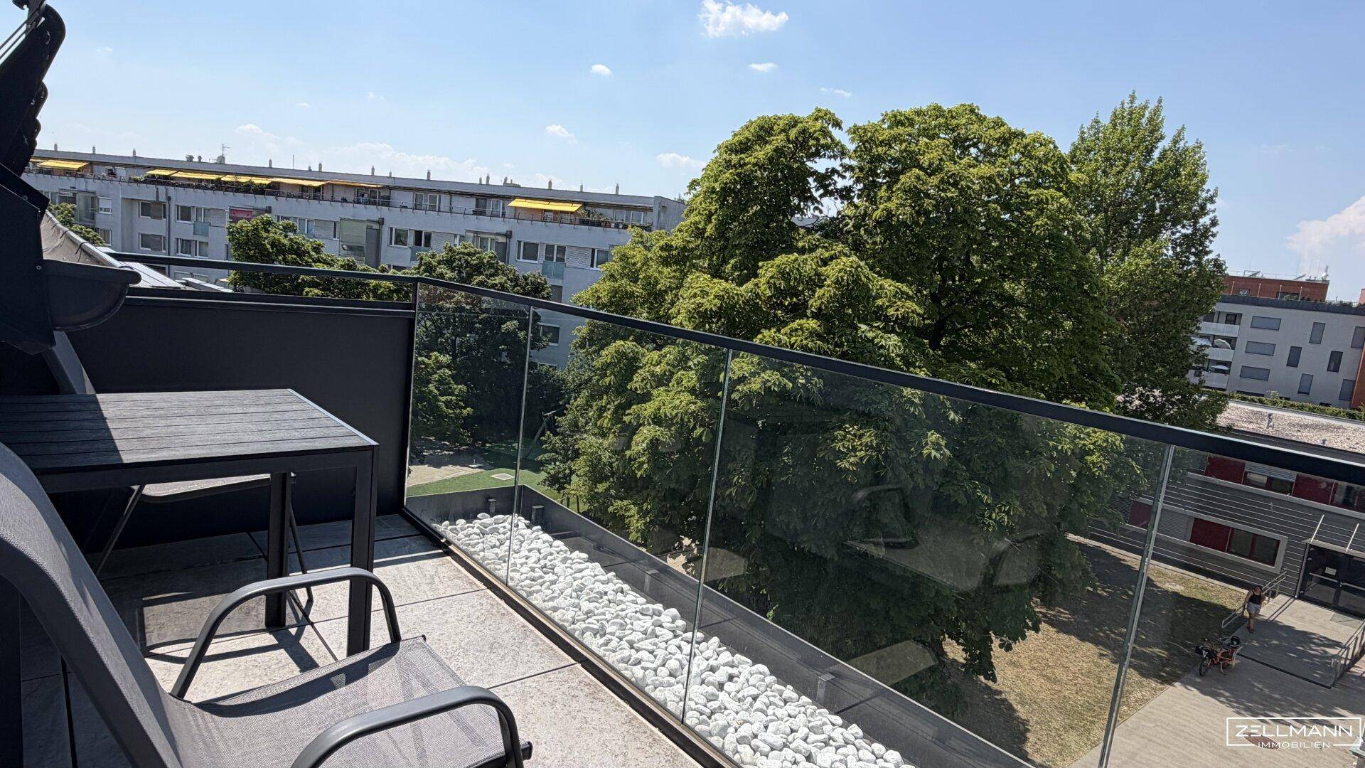 Geräumiger Balkon mit modernen Sitzmöbeln und weitem Blick über die Umgebung.