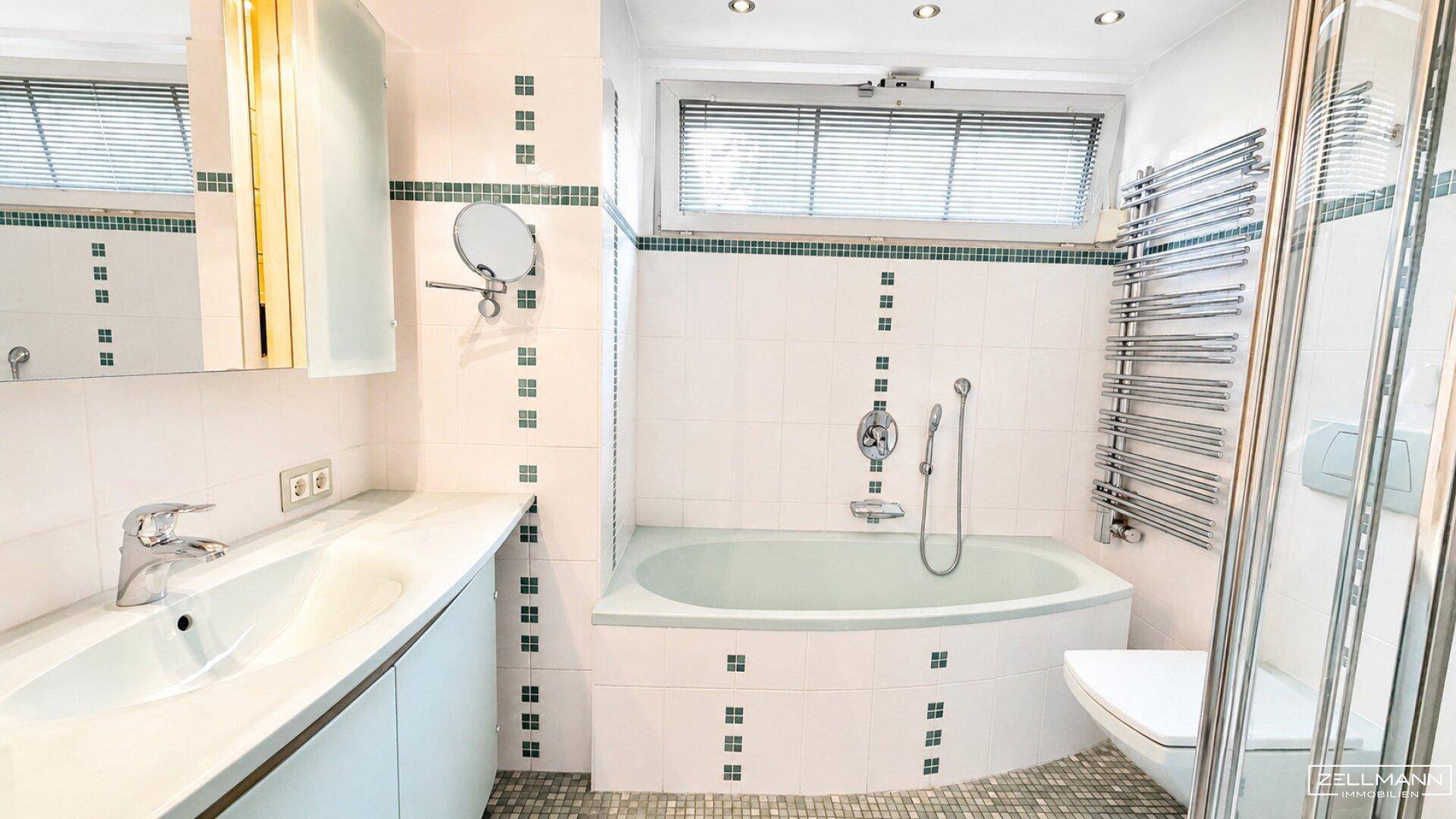 Badezimmer mit Badewanne, Dusche, Einzelwaschbecken und beheiztem Handtuchhalter.