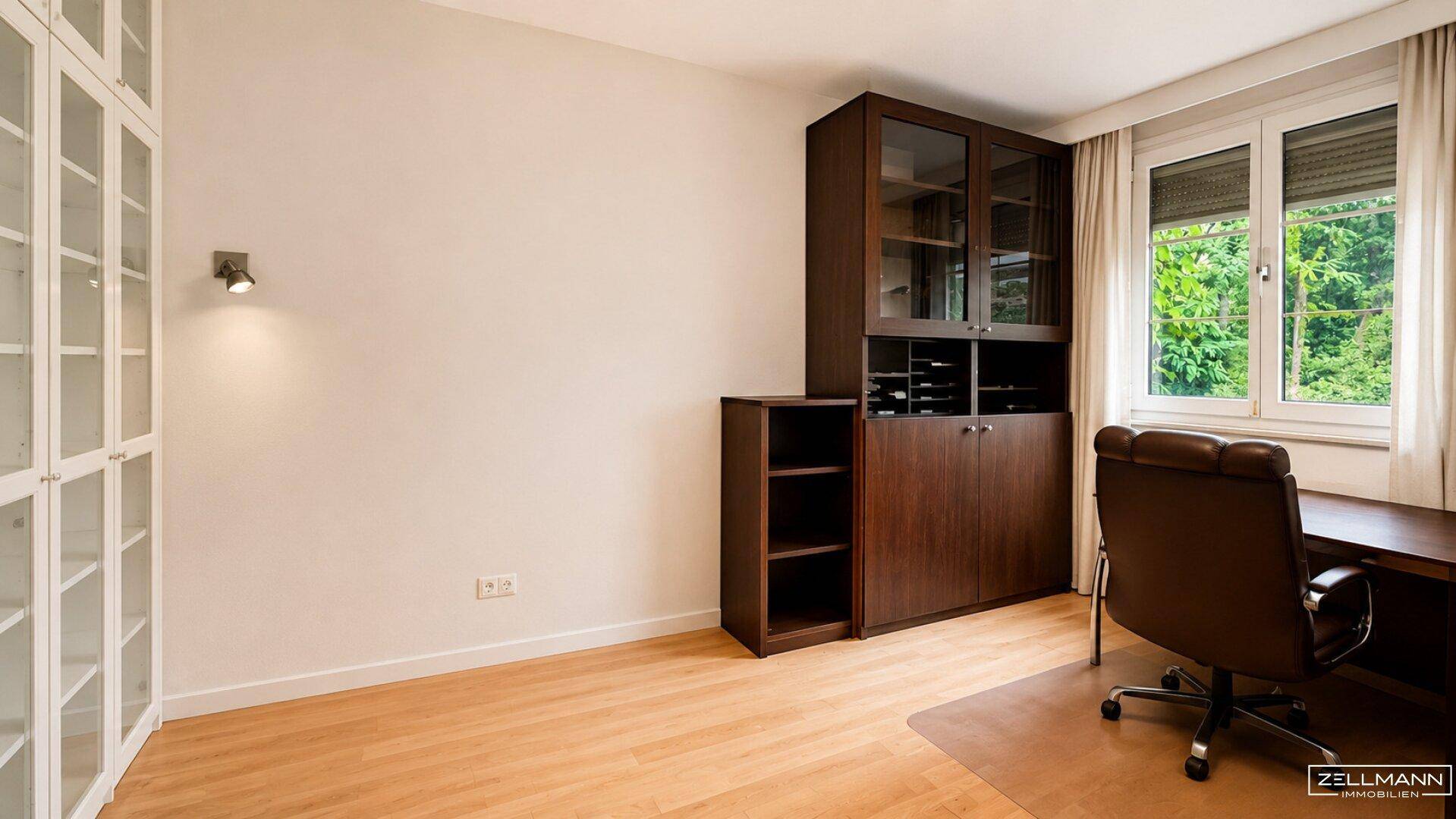 Helles Arbeitszimmer mit Holzfußboden, großem Fenster und Blick ins Grüne.
