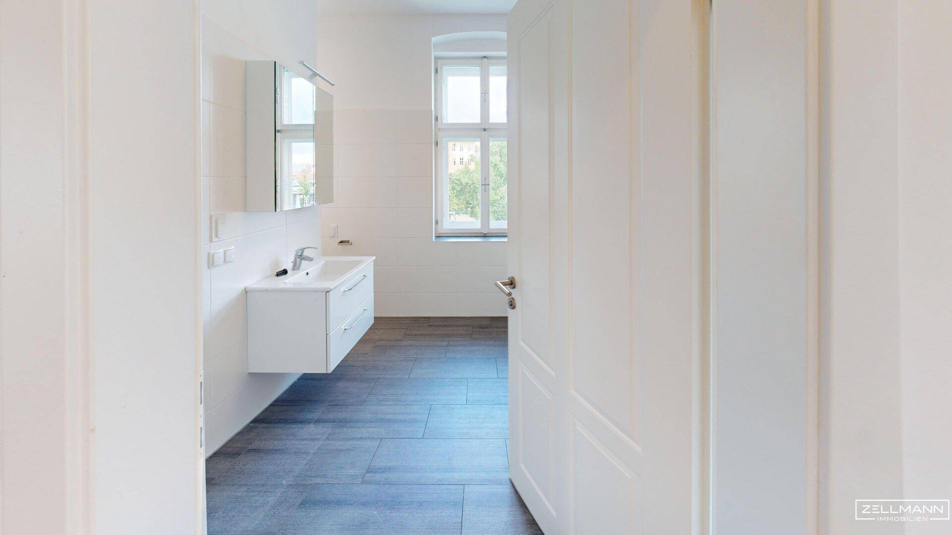 Modernes Badezimmer mit schwebendem Waschtisch, Spiegelschrank und Fenster.