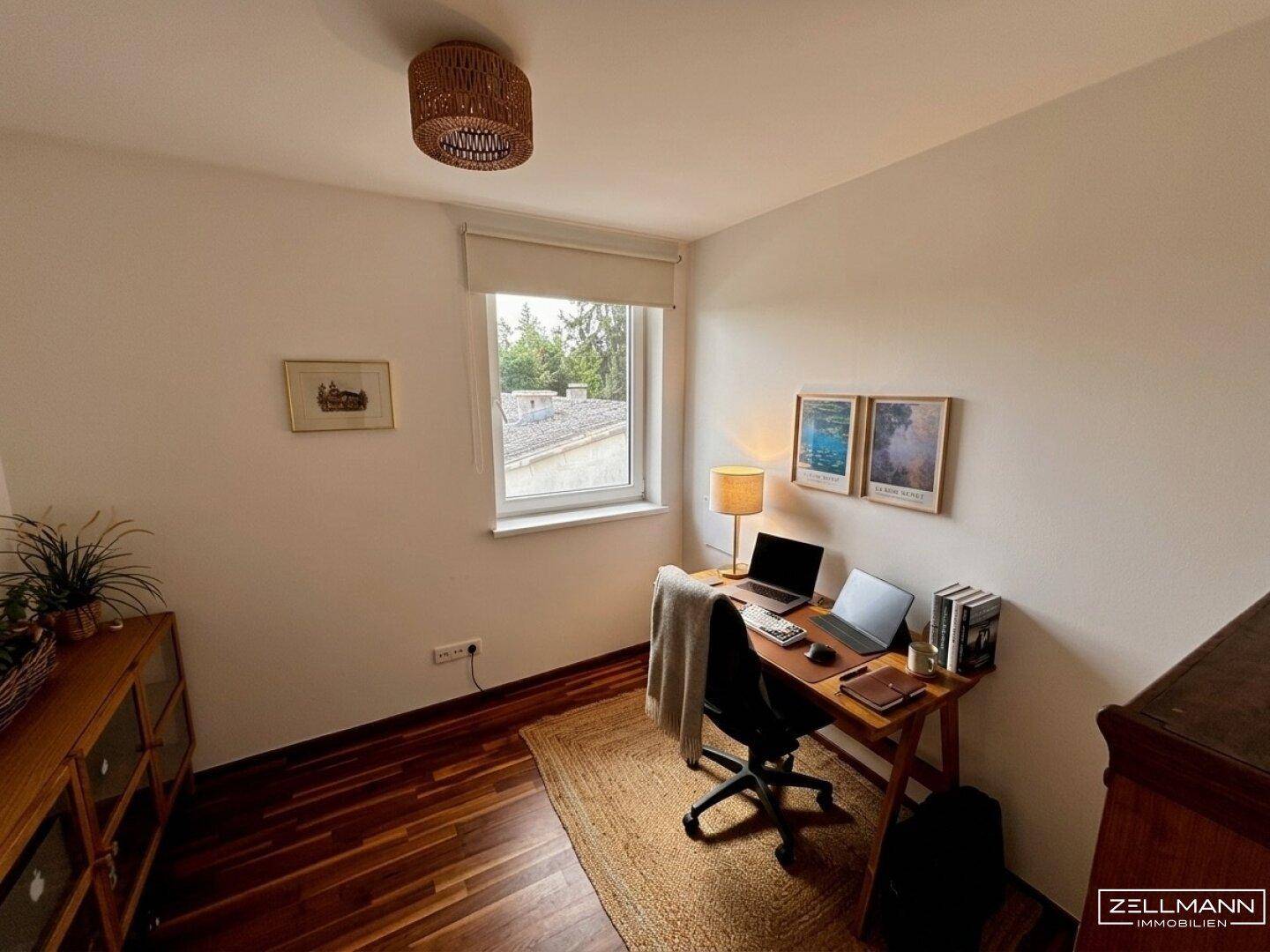Ruhiges Arbeitszimmer mit Holzboden, Schreibtisch und Blick ins Grüne.