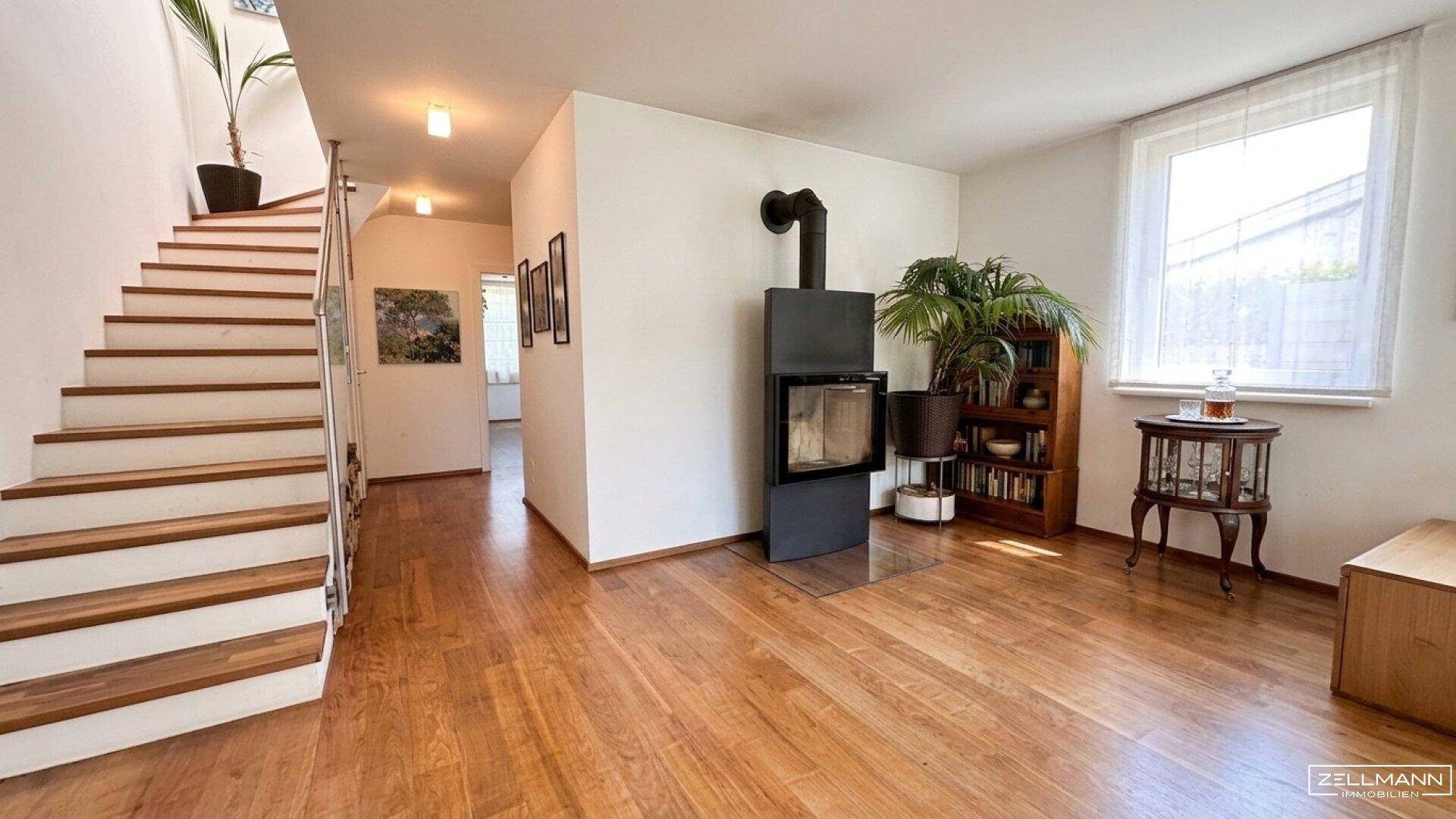 Heller Eingangsbereich mit Holztreppe, Holzboden und modernem Kaminofen.