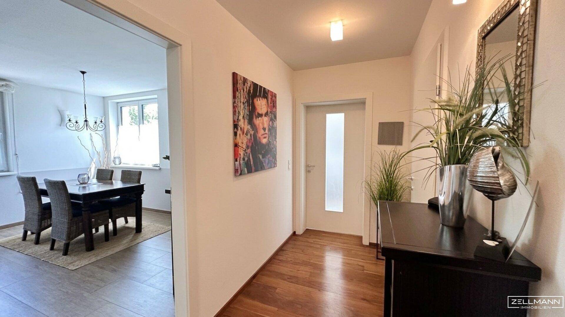 Heller Flur mit Holzboden, moderner Dekoration und Blick in den Essbereich.