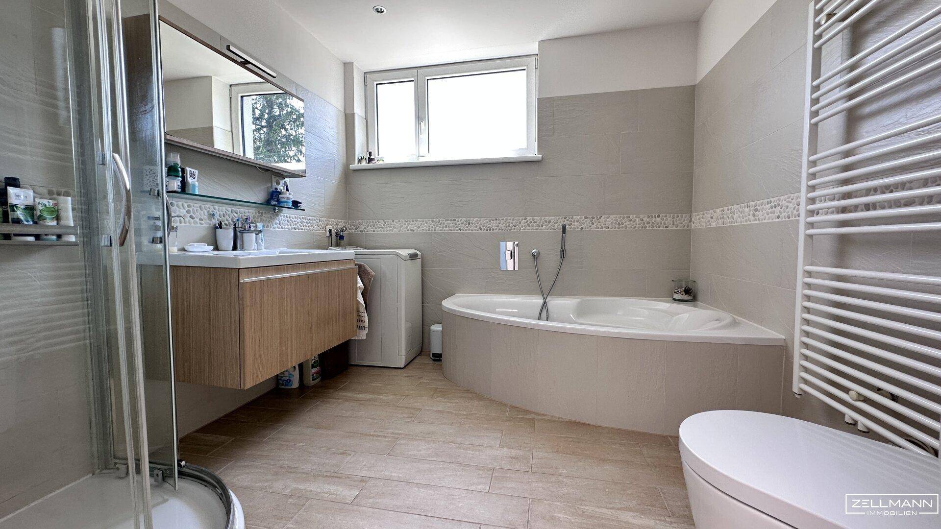 Modernes Badezimmer mit Badewanne, Dusche, Doppelwaschbecken und Fenster.