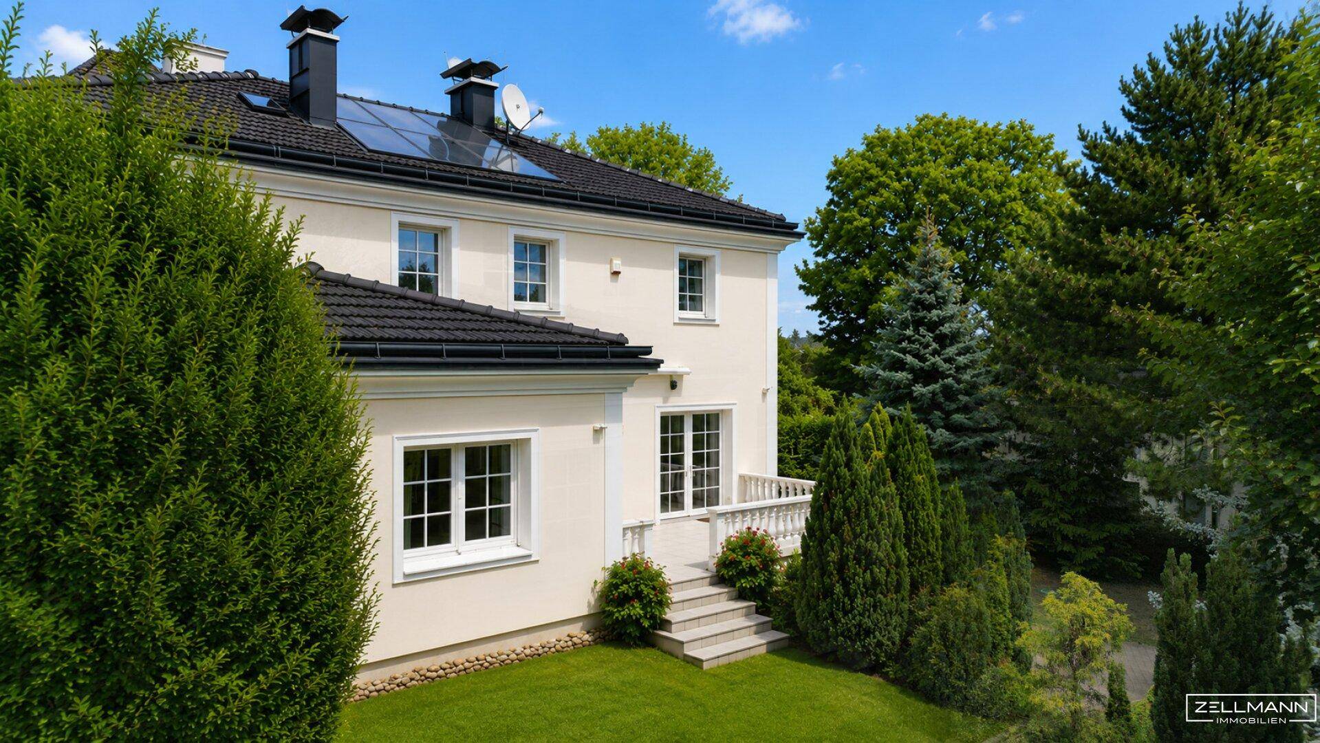 Elegantes Haus mit heller Fassade, dunklem Dach, Solaranlage und gepflegtem Garten.