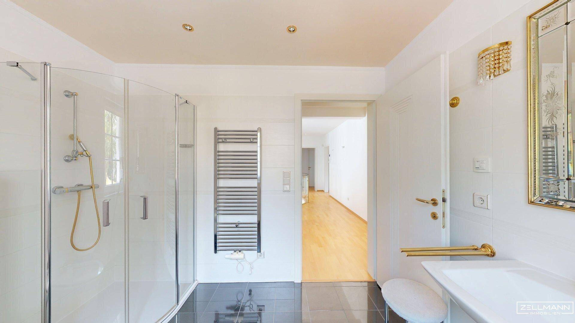 Modernes Badezimmer mit Glasdusche, beheiztem Handtuchhalter und elegantem Waschtisch.